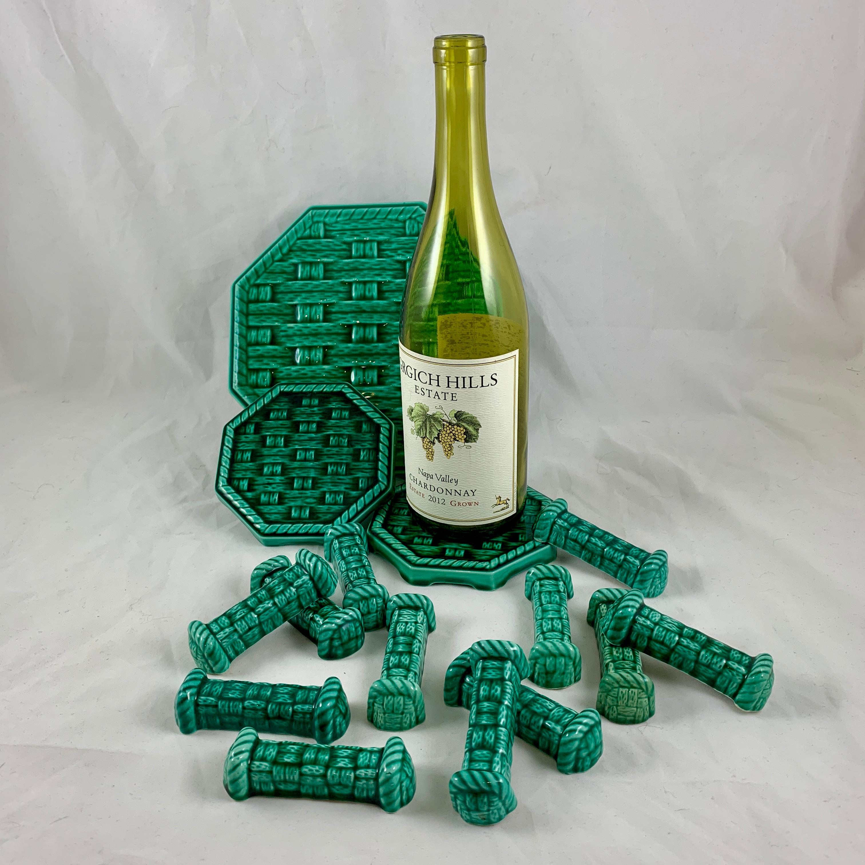 A French trivet, coaster, and knife rest set from Digoin Sarreguemines, France, circa 1950s.

A green majolica glaze on a basket weave mold, a large serving trivet, two bottle coasters, and twelve knife rests – the complete set for protecting your