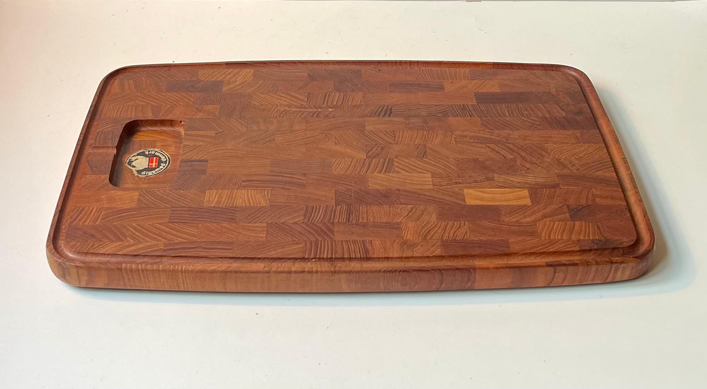 Large and heavy cutting board in solid stacked teak. Suitable for cheese, fruit or meats. Designed by Flemming Digsmed and manufactured by his Company Digsmed during the late 1960s or early 70s. Similar in design and quality to pieces from IHQ and