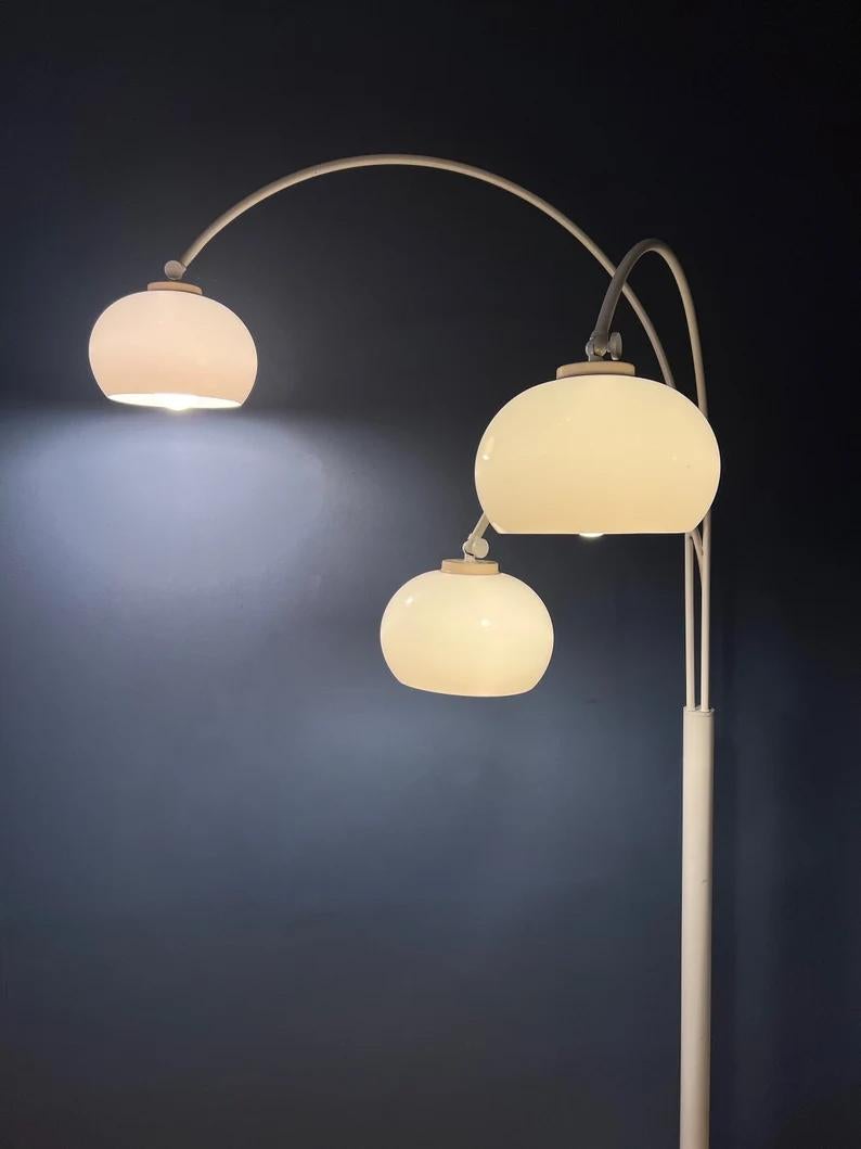 Dijkstra's famous triple arc floor lamp with acrylic mushroom shades. The shades produce a warm light and can be turned downwards or upwards. The arcs are flexible and can be aligned or positioned in opposite direction. The lamp requires three E27