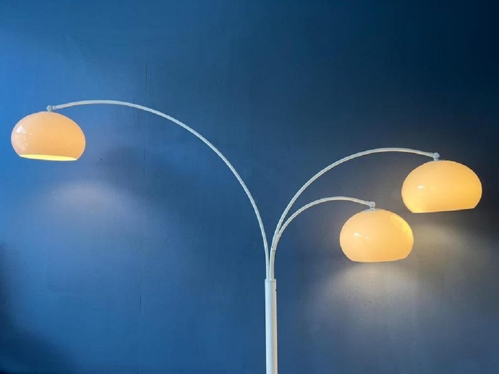 Dijkstra's famous triple arc floor lamp with acrylic mushroom shades. The shades produce a warm light and can be turned downwards or upwards. The arcs are flexible and can be aligned or positioned in opposite direction. The lamp requires three