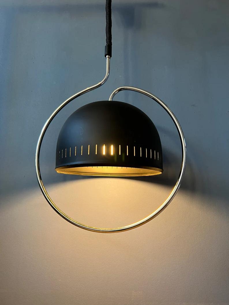 Dijkstra space age pendant lamp with chrome frame and black shade. The light escapes beautifully through the black escape and reflects nicely on the chrome frame. The height of the lamp can easily be adjusted with the rise/fall mechanism. The lamp