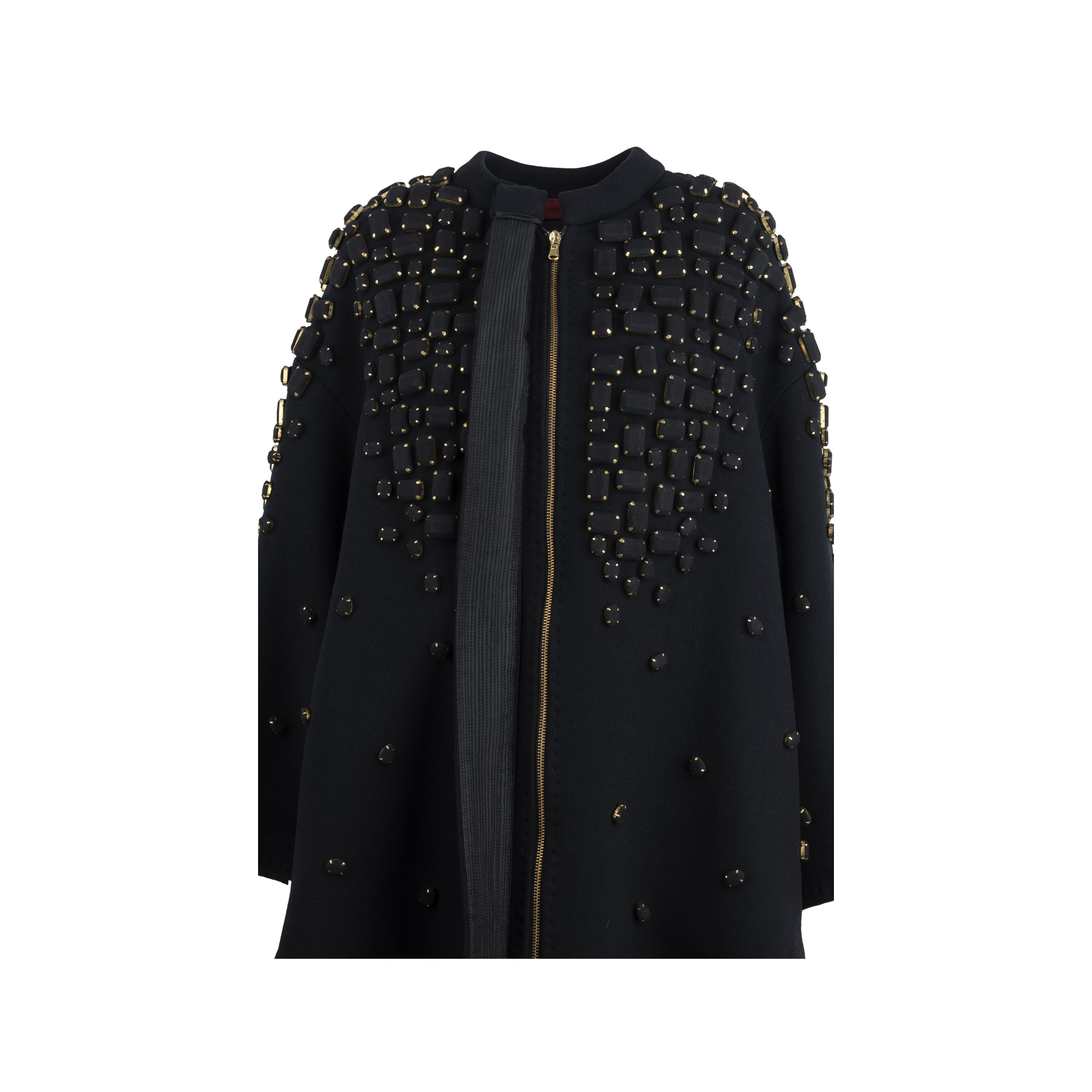 This Diliborio Embelished Jacket is a luxurious garment made with black cotton fabric. Featuring a cape styled bell-shaped model, long sleeves, and a hidden zip closure, this jacket is adorned with beautiful black and gold applications for a look