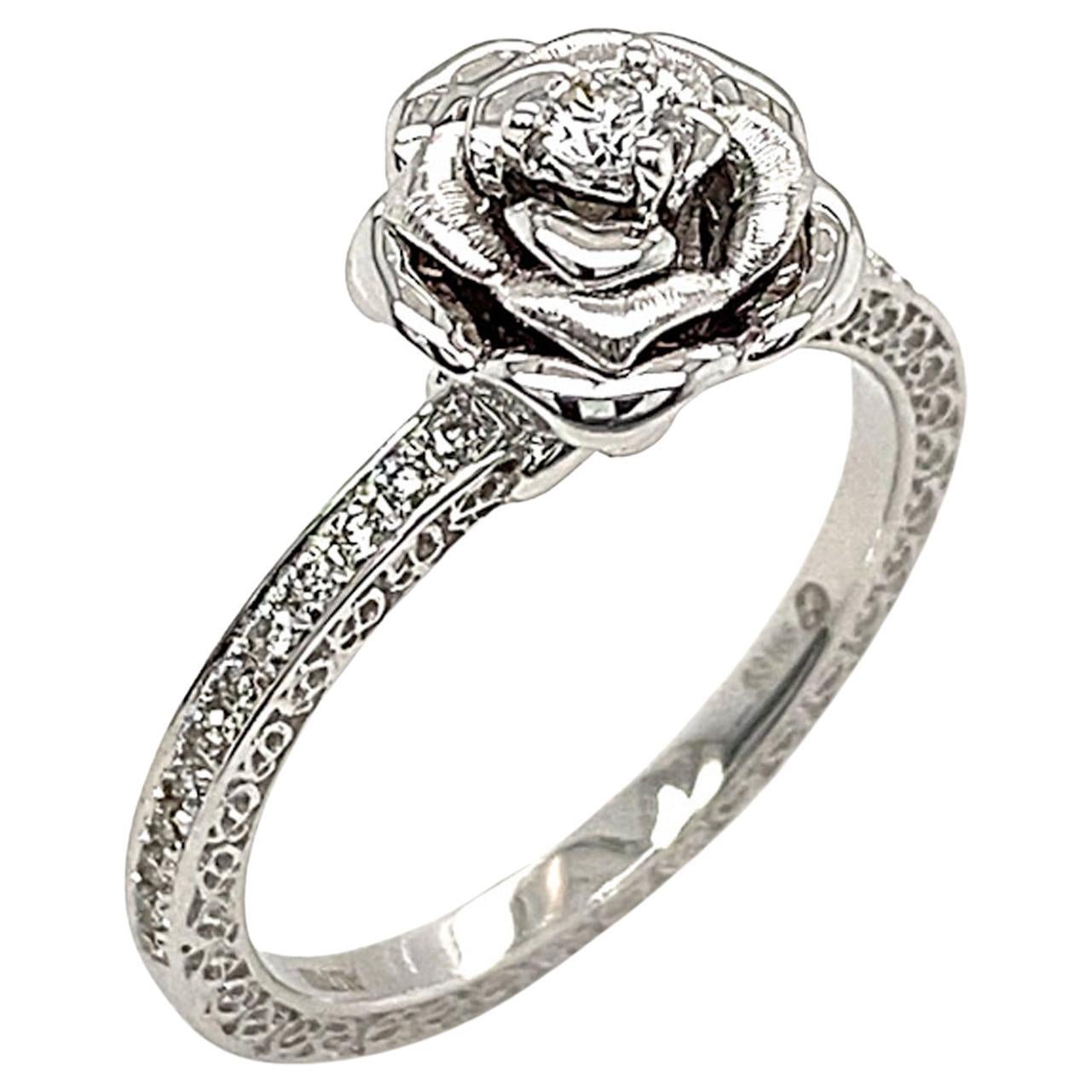 Eine blühende Rose - das universelle Symbol für Liebe, Schönheit und Dankbarkeit. 

Der Blooming Rose Solitaire Diamond Ring von Dilys' zeichnet sich durch einen runden Solitär-Diamanten (0,08 ct) in der Mitte des Rings aus, der von 24 Diamanten