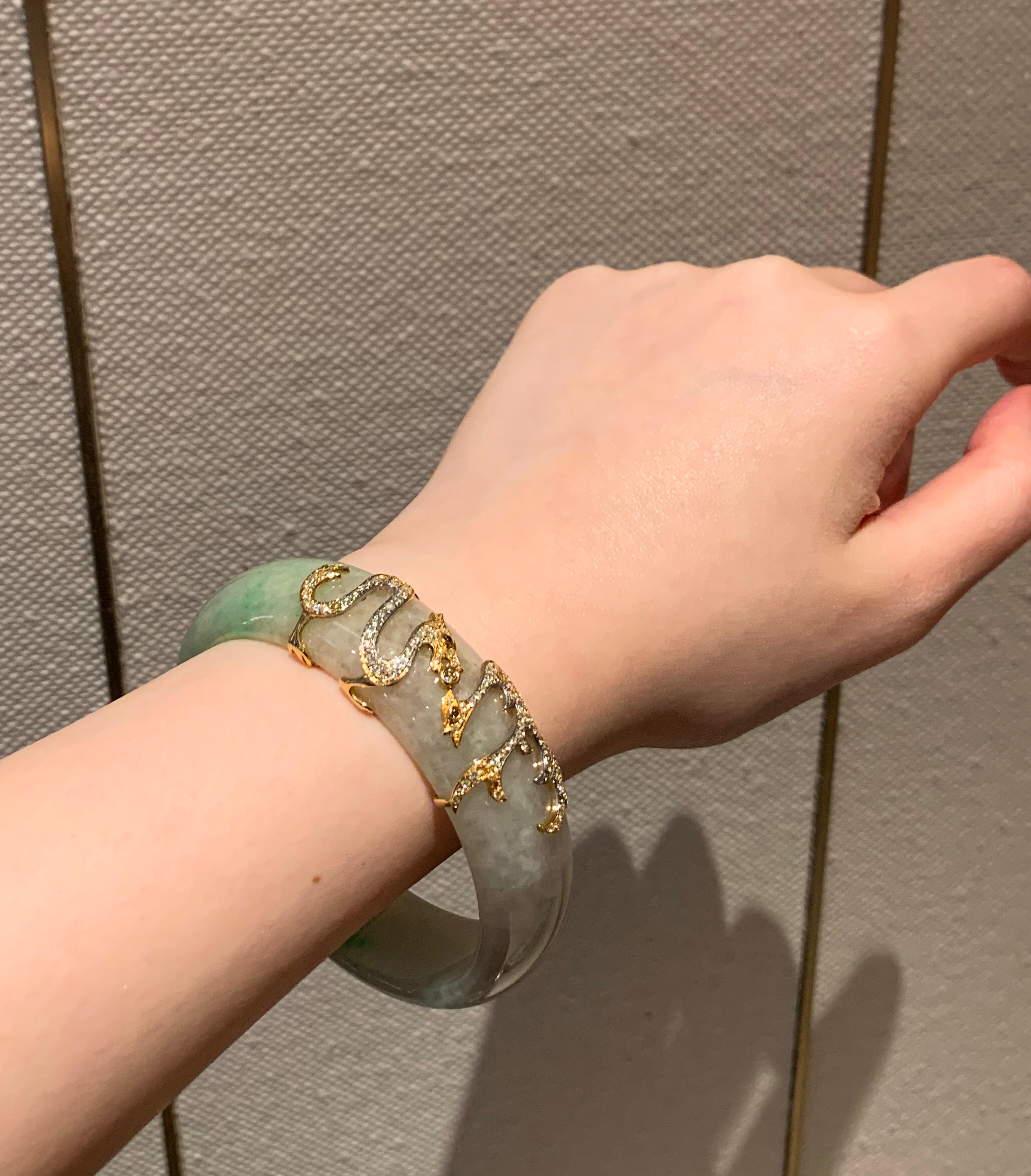 The House of Dilys’ presents the jade bangle with a modern twist. Bringing out the colours of this HKJSL certified 311.16-carat natural jade bangle is the 18 karat gold dragon guard, set with 100 fancy color diamonds, totaling .96 carat. This