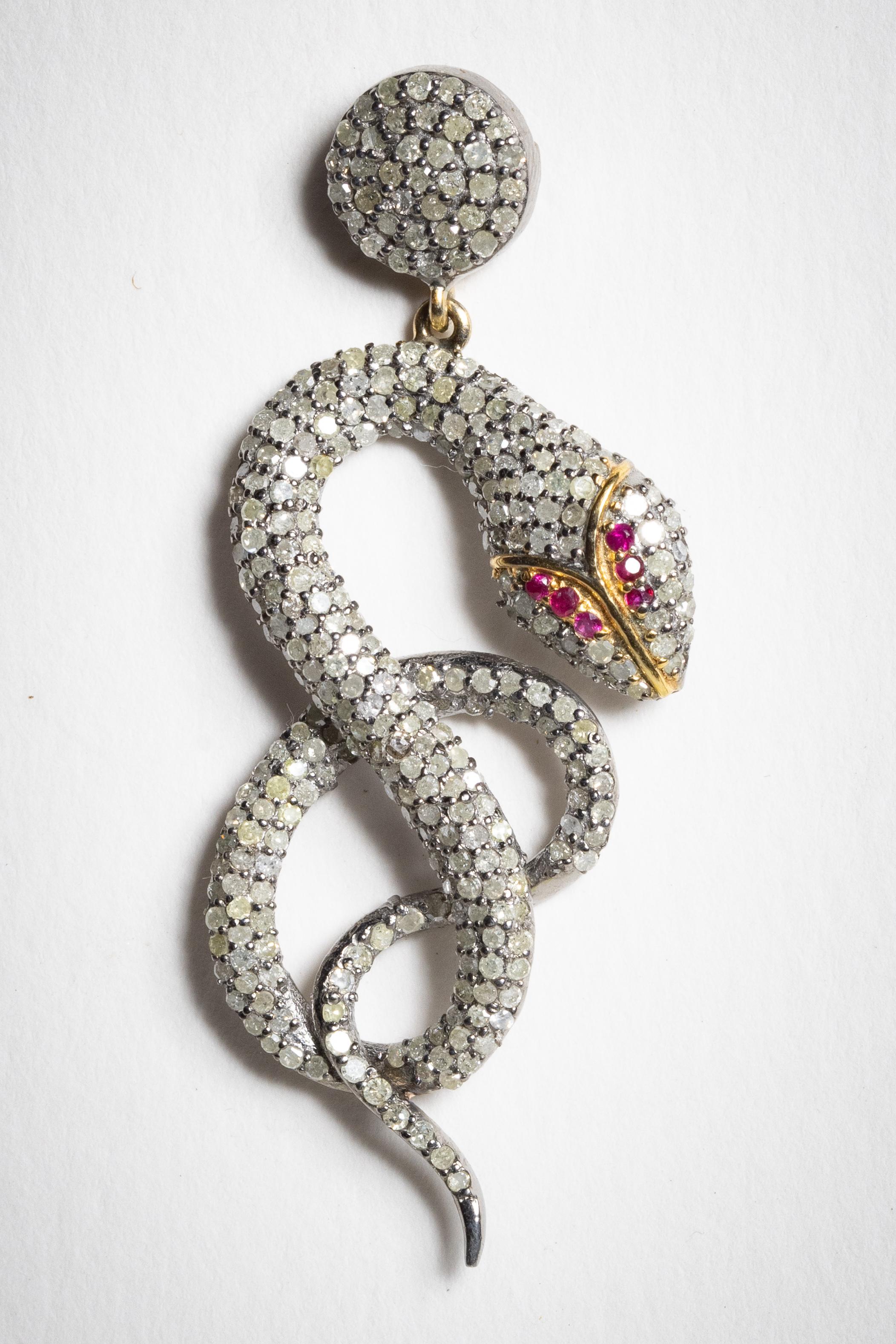 An incredible pair of coiled snake diamond earrings with ruby eyes.  The diamonds are round, brilliant cut diamonds in a pave` setting and the eyes on each are 6 round faceted rubies.  All set in sterling silver with an 18K gold post for pierced