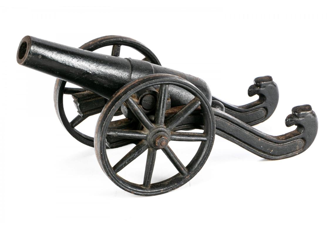 With large wheels and curved eagle head back ends. Hole for a pin on the cannon end. 
L. 14 1/2