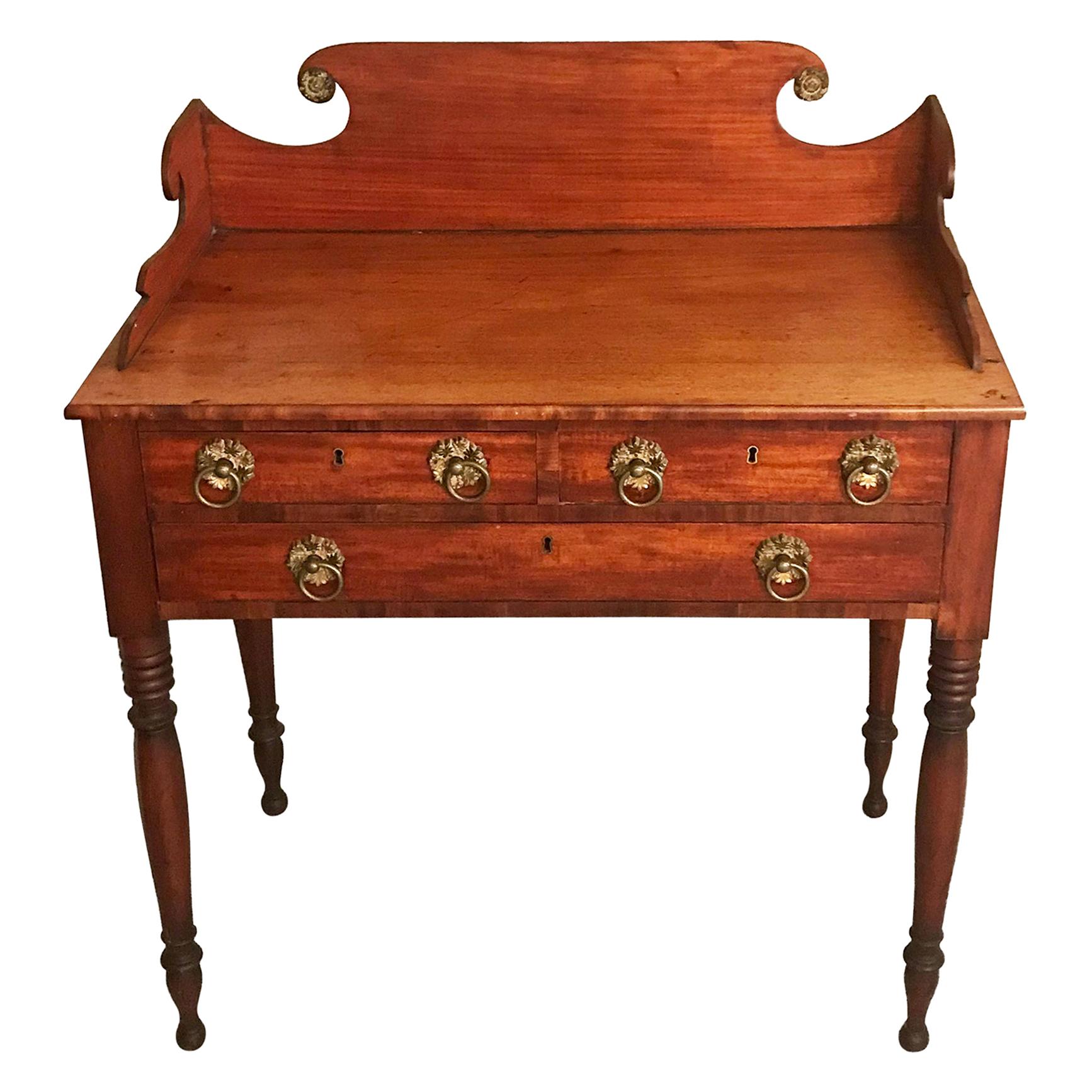 Three drawer mahogany and mahogany veneer server with a high scrolled back splash above two short and one long drawer sitting on turned legs, retaining
original fire gilt brass pulls. New York, circa 1820.



  