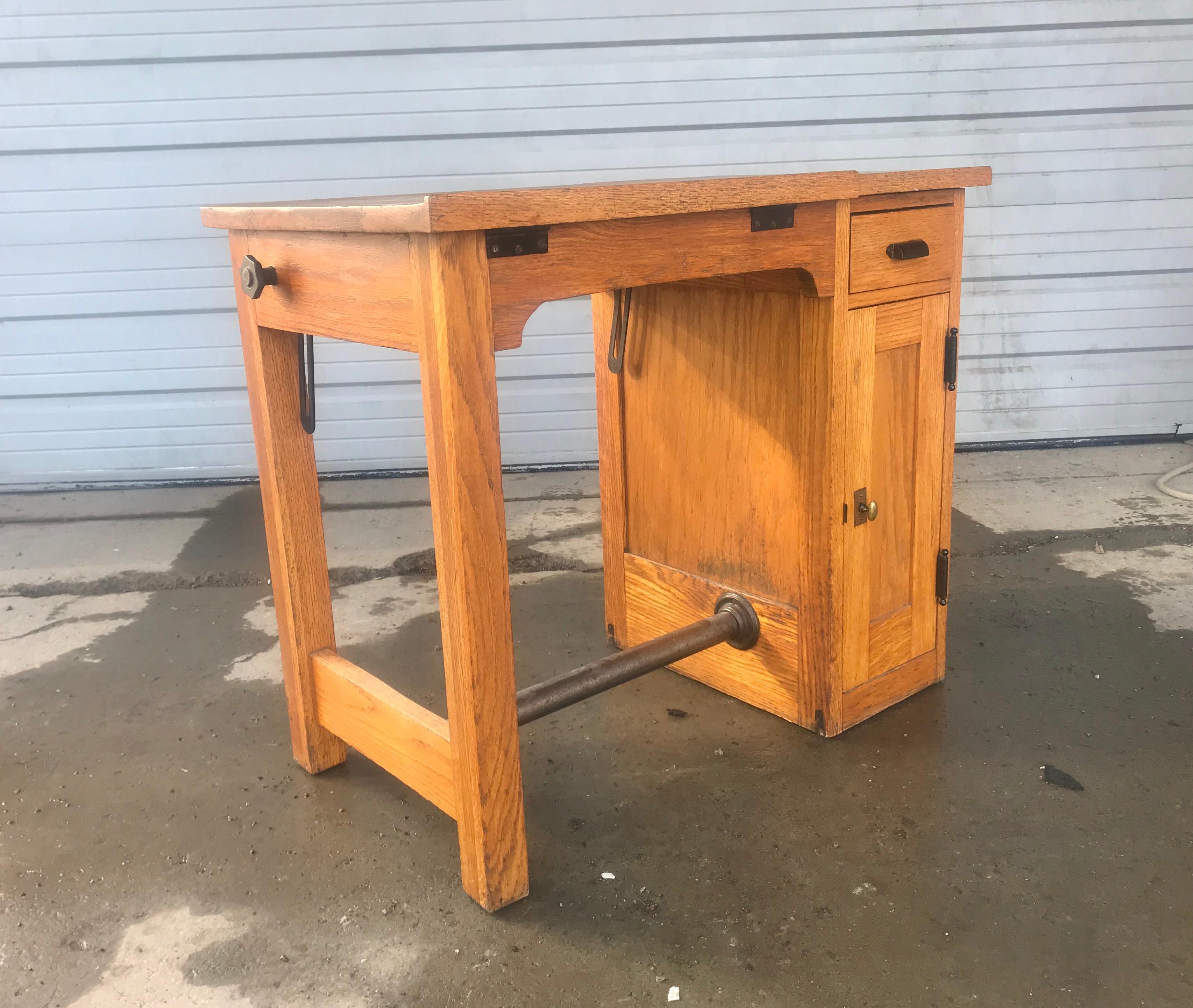 Diminutive antique oak architects desk, drafting table, adjustable top, great size, featuring top right drawer and bottom right storage, slots for renderings. Retains original warm oakwood finish, patina, cast iron footrest and hand pull. Hand