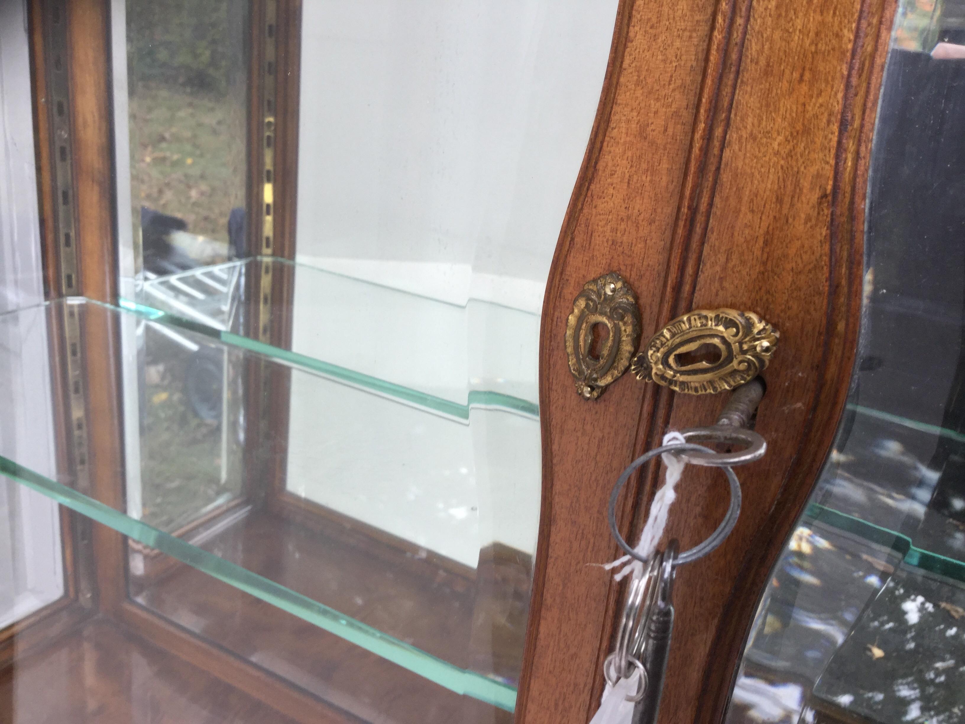 Diminutive Biedermeier cabinet with beveled glass. This cabinet is only 56” tall by 38” wide by 10 1/2” deep. It has 2 thick adjustable glass shelves, one has a small chip. No shelves in the bottom. It has 3 minor repairs. One on each front foot and