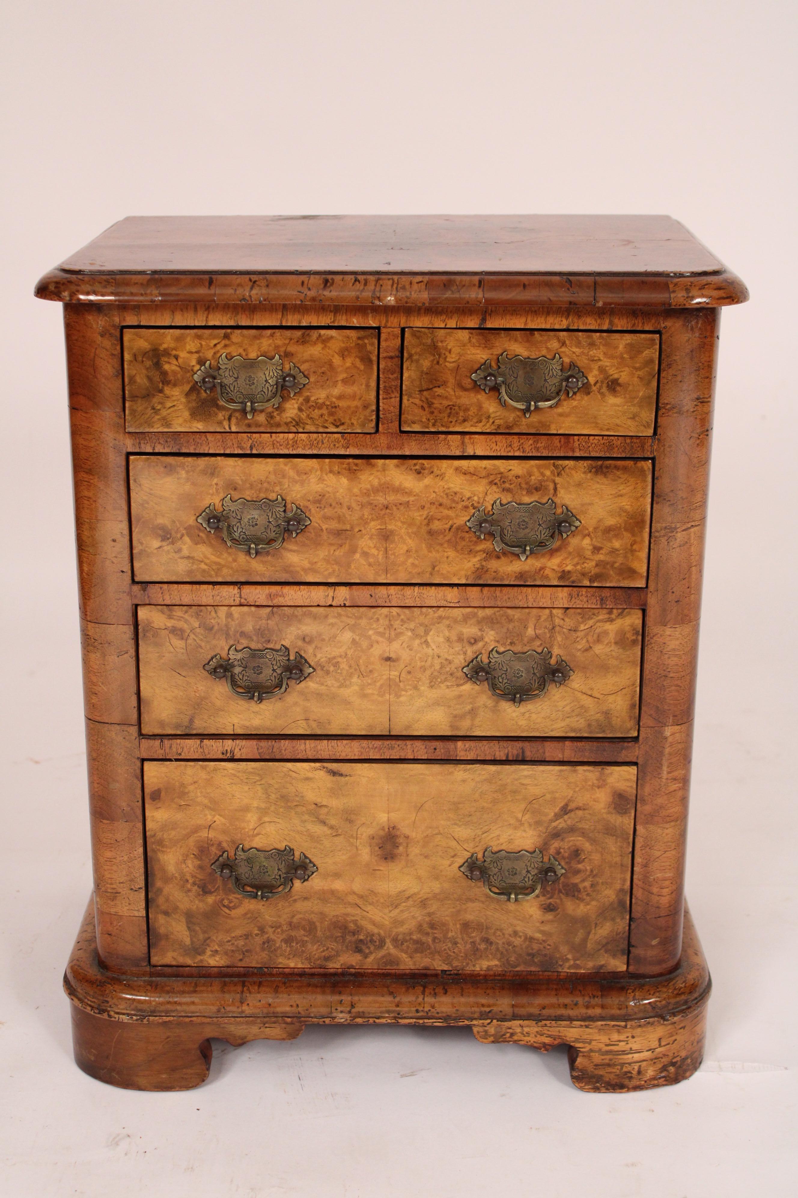 Diminutive Edwardian style thuya and walnut chest of drawers, circa 1900. With a thuya thumb molded rectangular top, two thuya top drawers over 3 graduated lower drawers all with brass hardware,  walnut sides, resting on a molded base with bracket