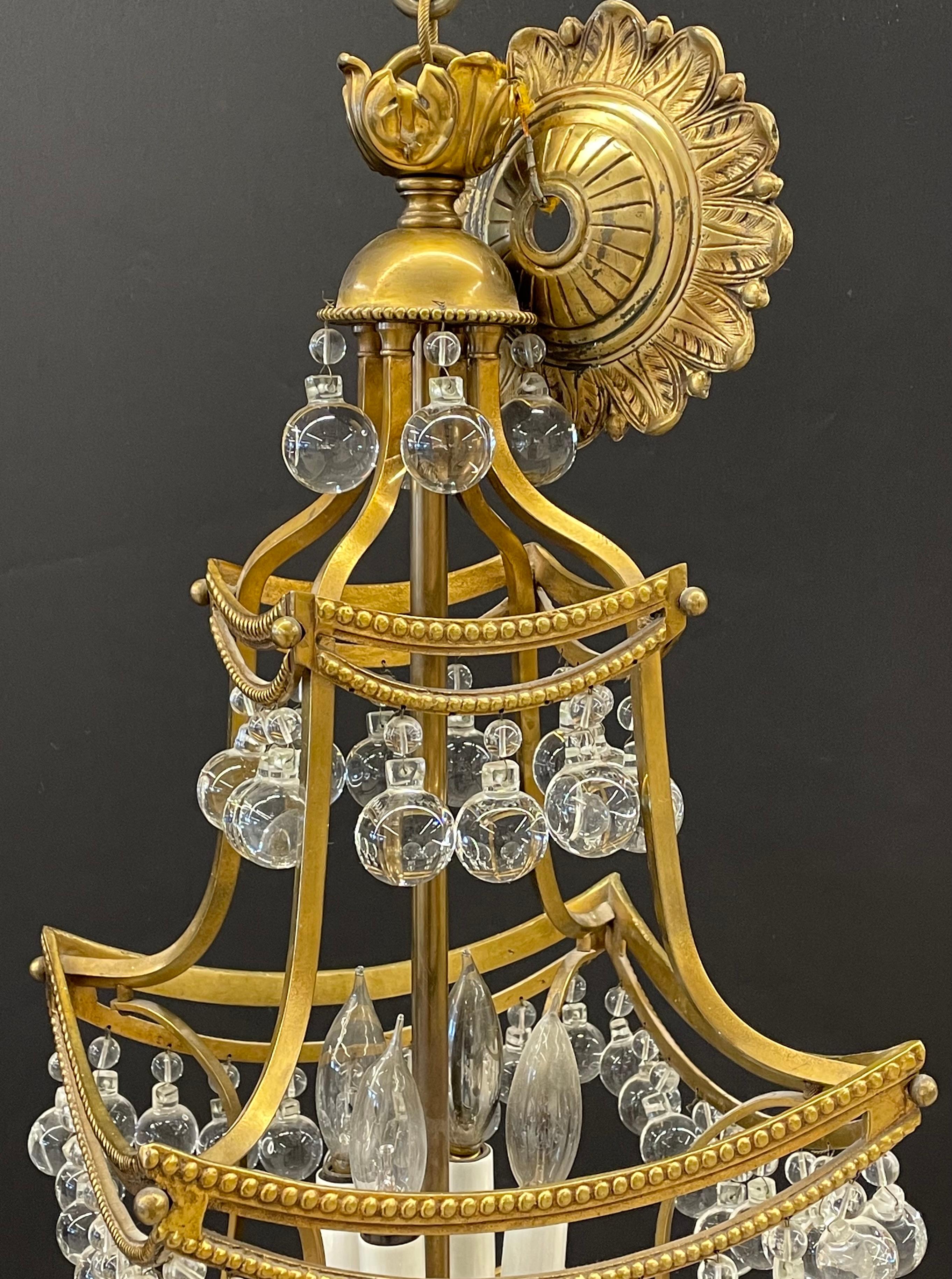 Bronze and crystal pagoda form diminutive chandelier. Fine Hollywood Regency chandelier of cast bronze and circular crystal prisms. Having four lights, small chain and canopy.