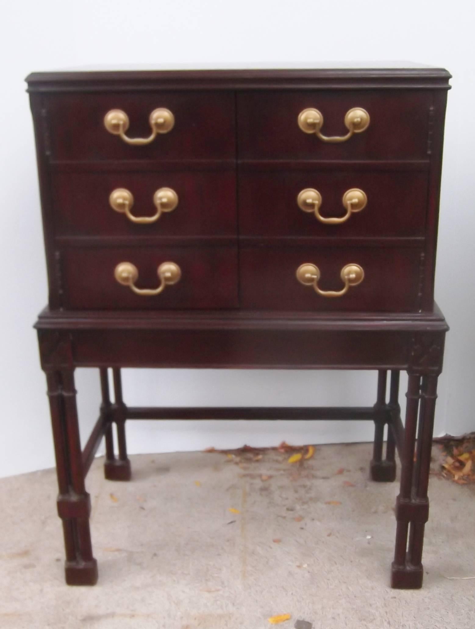 A mahogany chest on stand with faux drawers that reveal a storage compartment.
The Classic handles make the front appear as six small drawers but are actually two doors. The base is attached and the legs are I the Regency style. A perfect piece for