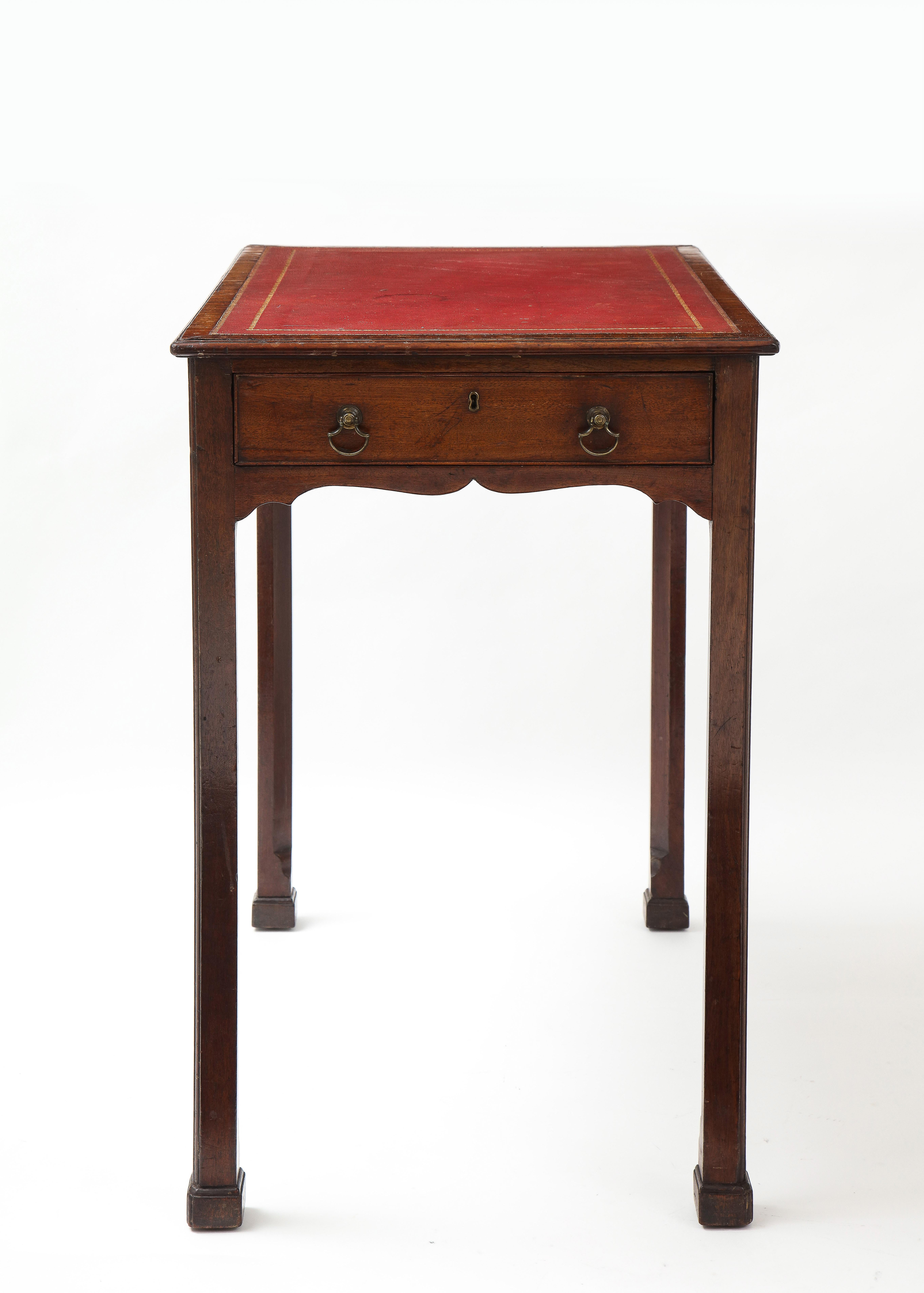 Very fine George III period mahogany diminutive writing table, the gilt tooled leather top over molded edge, the single drawer with original axe blade handles, over slightly scalloped apron and standing on square legs with inner chamfer and ending