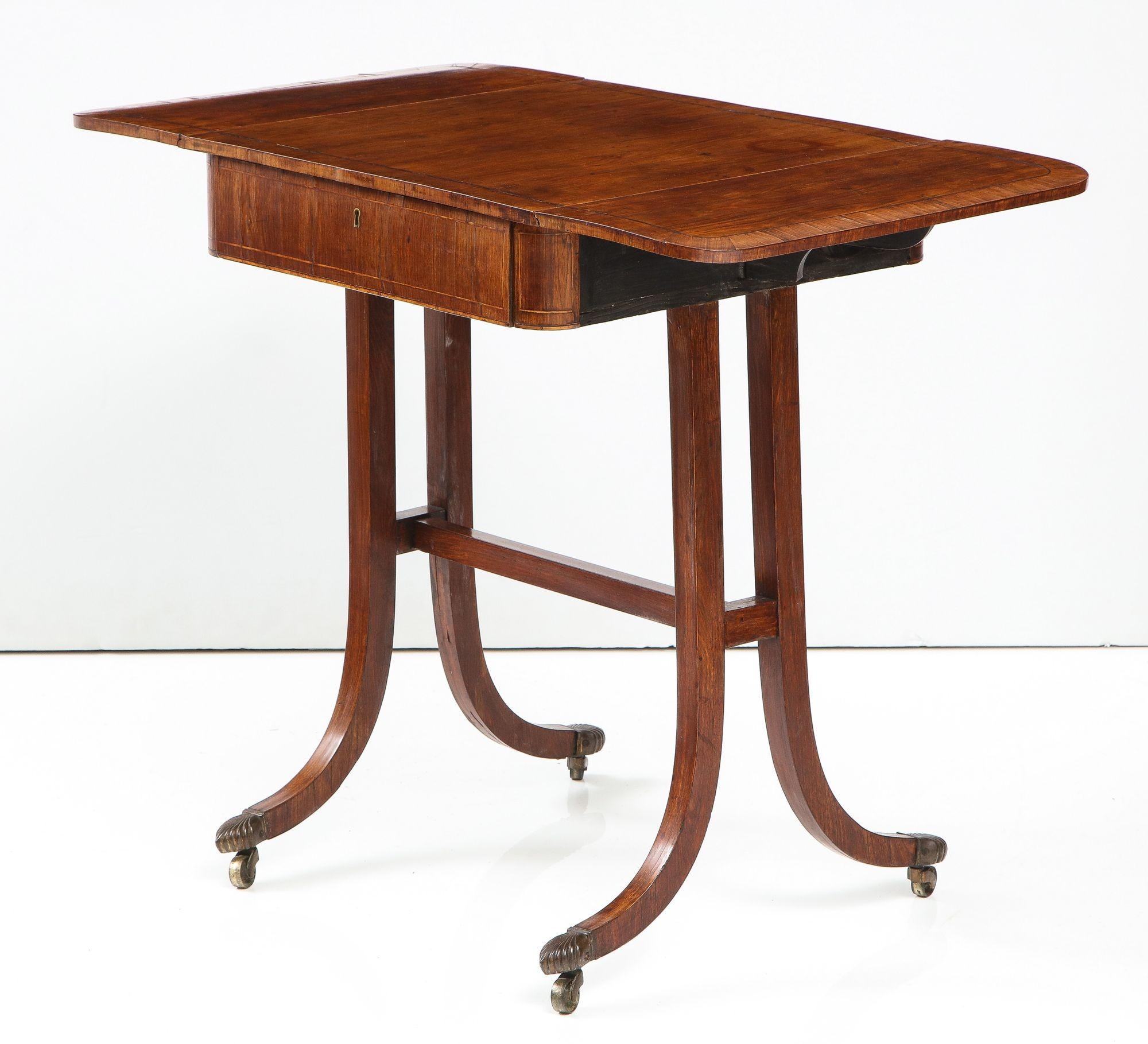 Rare, fine and diminutive cocuswood sofa table, ex collection of Doris Duke, the top with ebony string inlay and purpleheart cross banding, having two flap leaves and single drawer and standing on down-swept legs joined by 