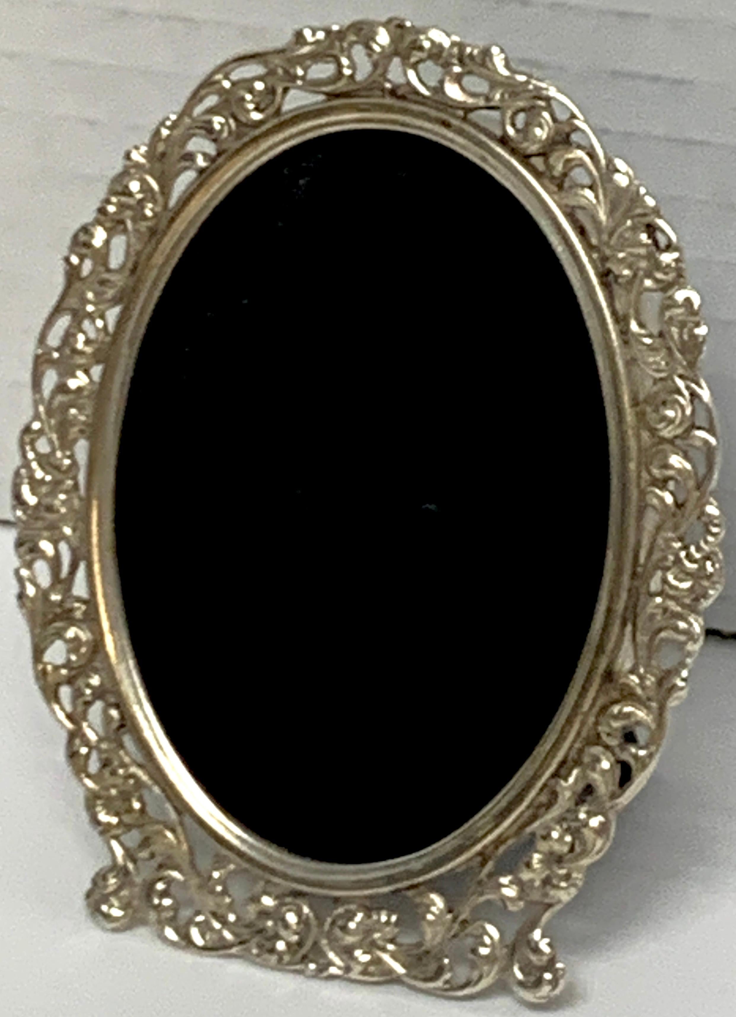 Diminutive continental pierced sterling oval frame, with convex glass and lacquered wood backing. Holds a 2-inch x 2.25-inch photograph.