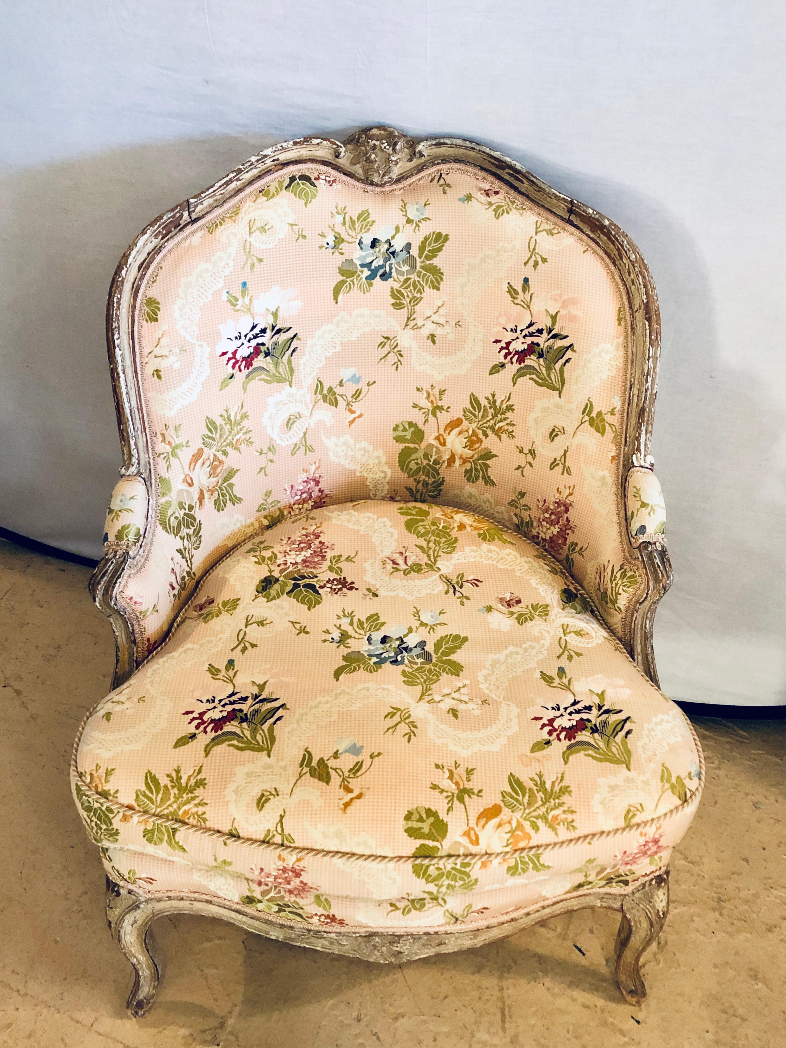 Late 19th or early 20th century diminutive distressed and paint decorated Louis XV style slipper chair in Scalmandre fabric. The wonderfully decorative bedroom or occasional chair is one of the finest you will find. Covered in a spectacular