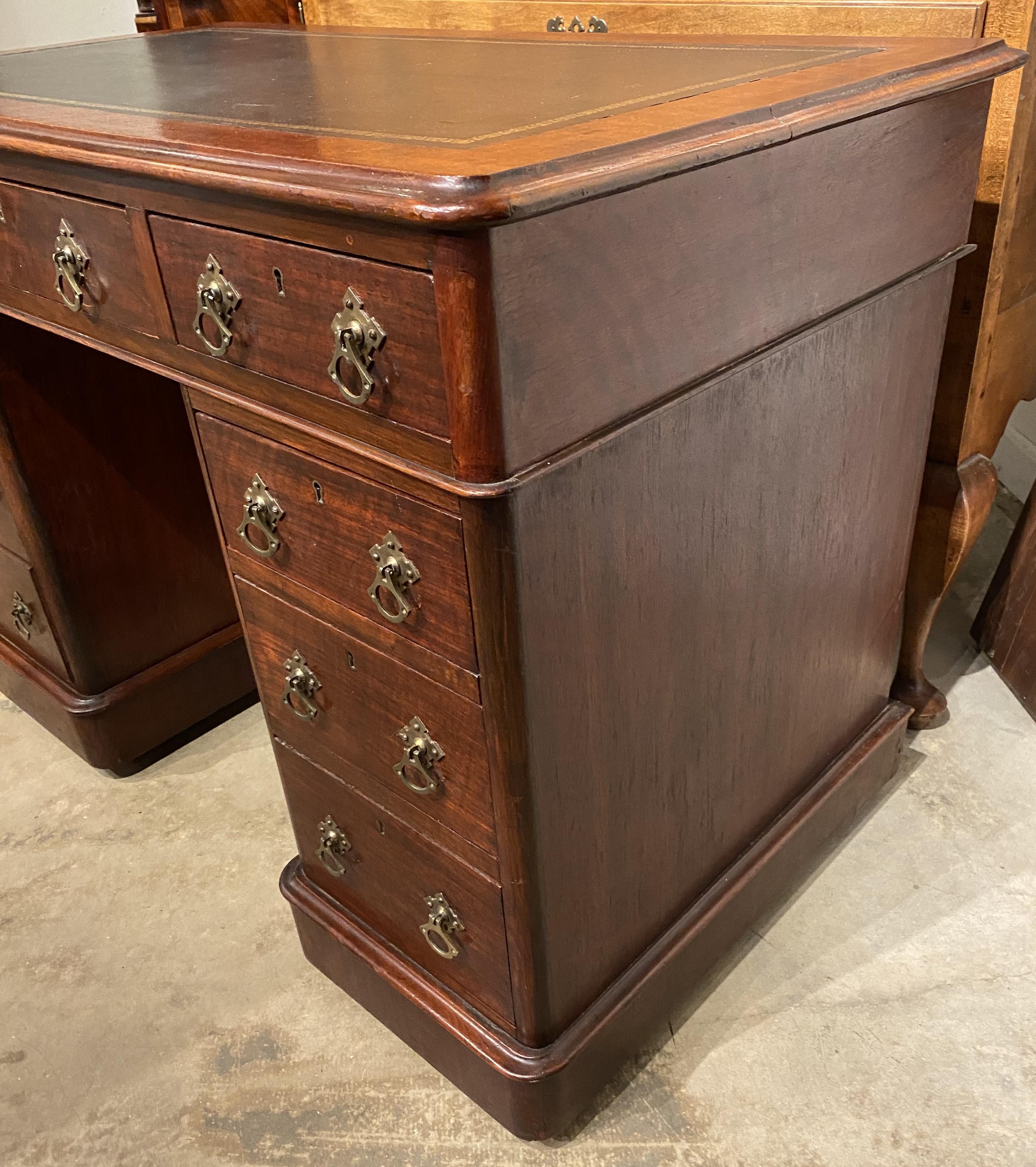 A fine diminutive Edwardian mahogany three part pedestal desk with leathered tool top and three fitted frieze drawers, with three additional fitted drawers on each pedestal, all with decorative brass pulls. Supported on casters, which need some