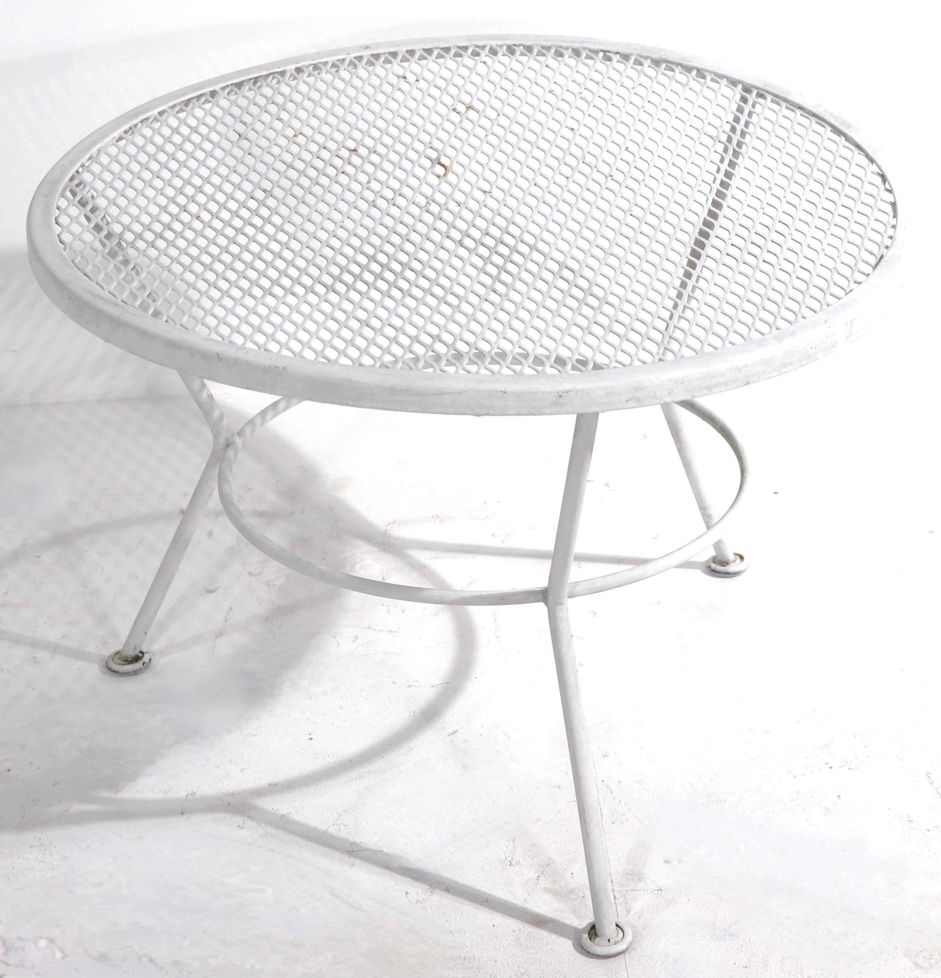 Architectural side, cocktail or end table with wrought iron base and metal mesh top. The table is currently in white paint finish, which shows cosmetic wear, normal and consistent with age. Usable as is or we offer custom powder coating if you