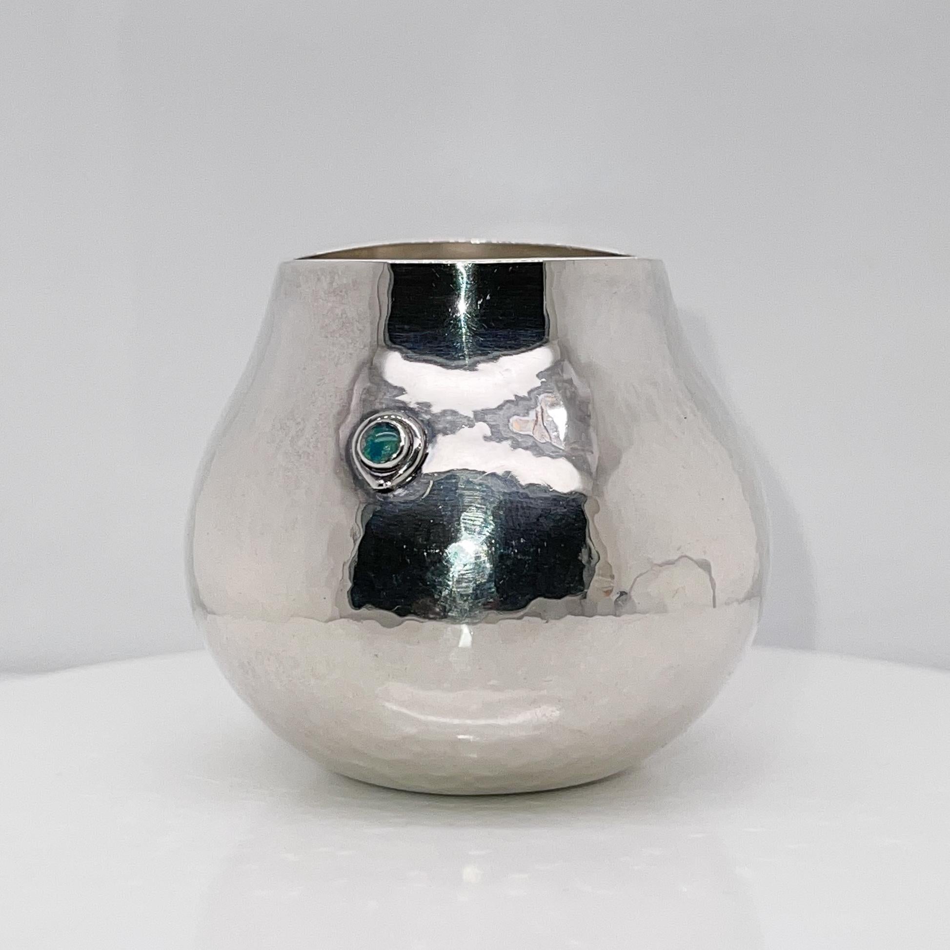 A wonderful 1980's handmade sterling silver vase.

By Kay Ivankovic. 

Kay Ivankovic, the high-level contemporary British silversmith, is known for her flowing, organic forms. 

This hand-chased vase has a bezel-set opal at its center and a
