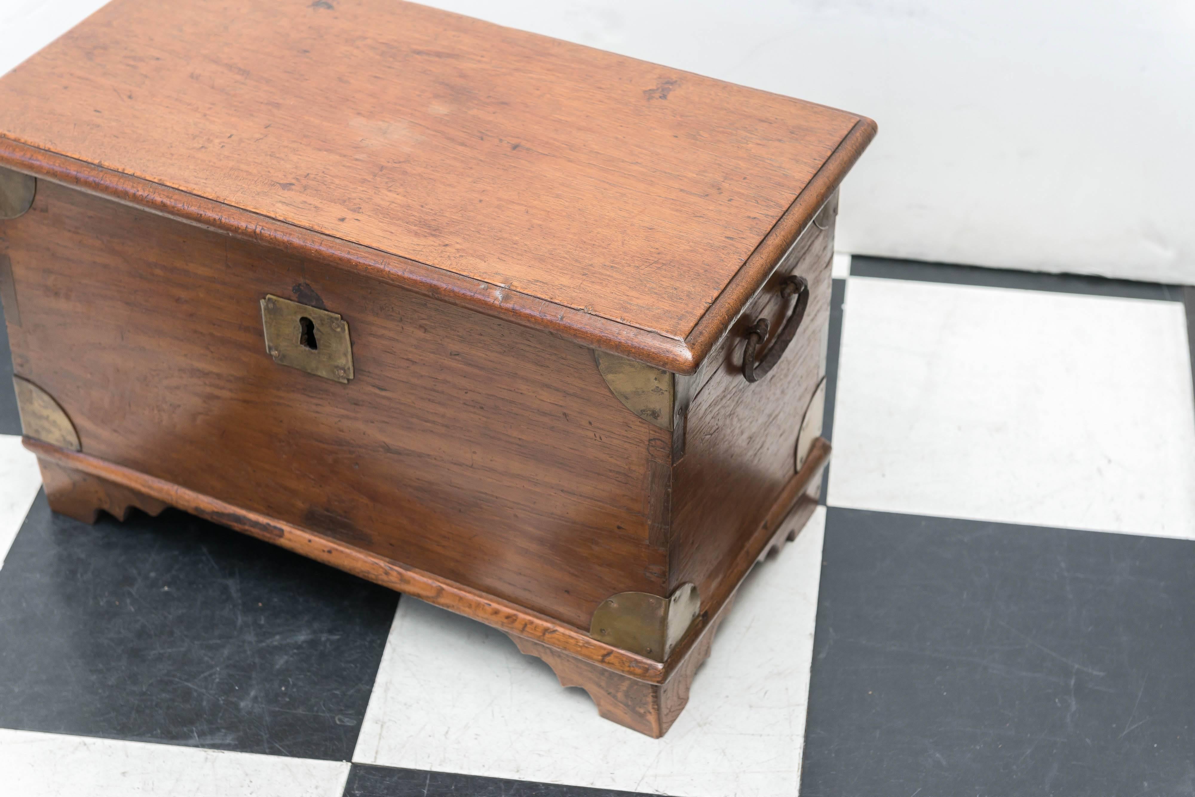 Diminutive late 19th century Anglo Indian trunk raised on small bracket feet. Plenty strong to sit on and tie your shoes. Lots of room for shoes and other treasures. Old brass handles and corners. Strong dovetail joinery. Useful as a step