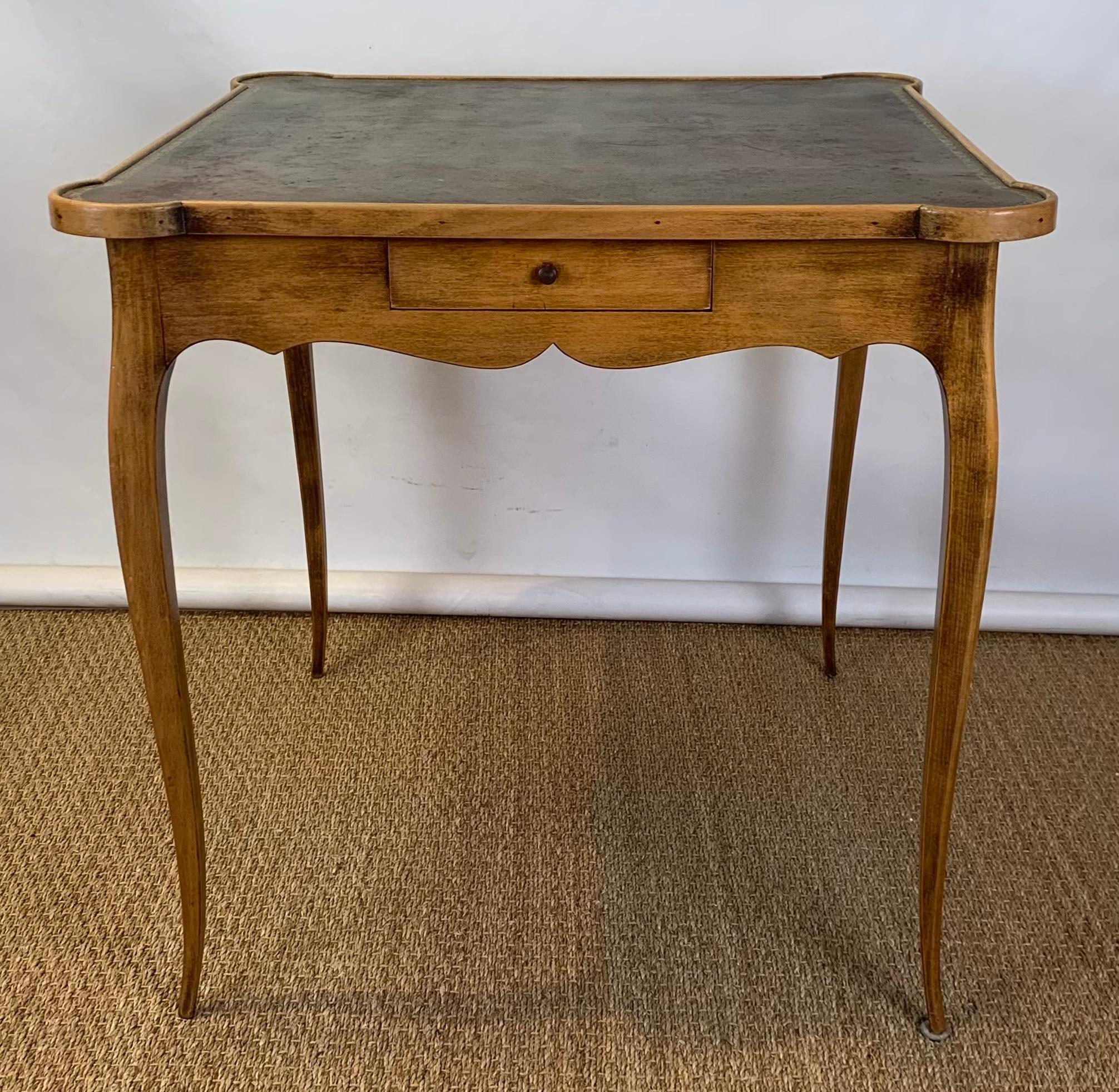 A small mid-20th century French style games table with tooled green-brown tooled leather top above single drawer resting on delicately carved legs.