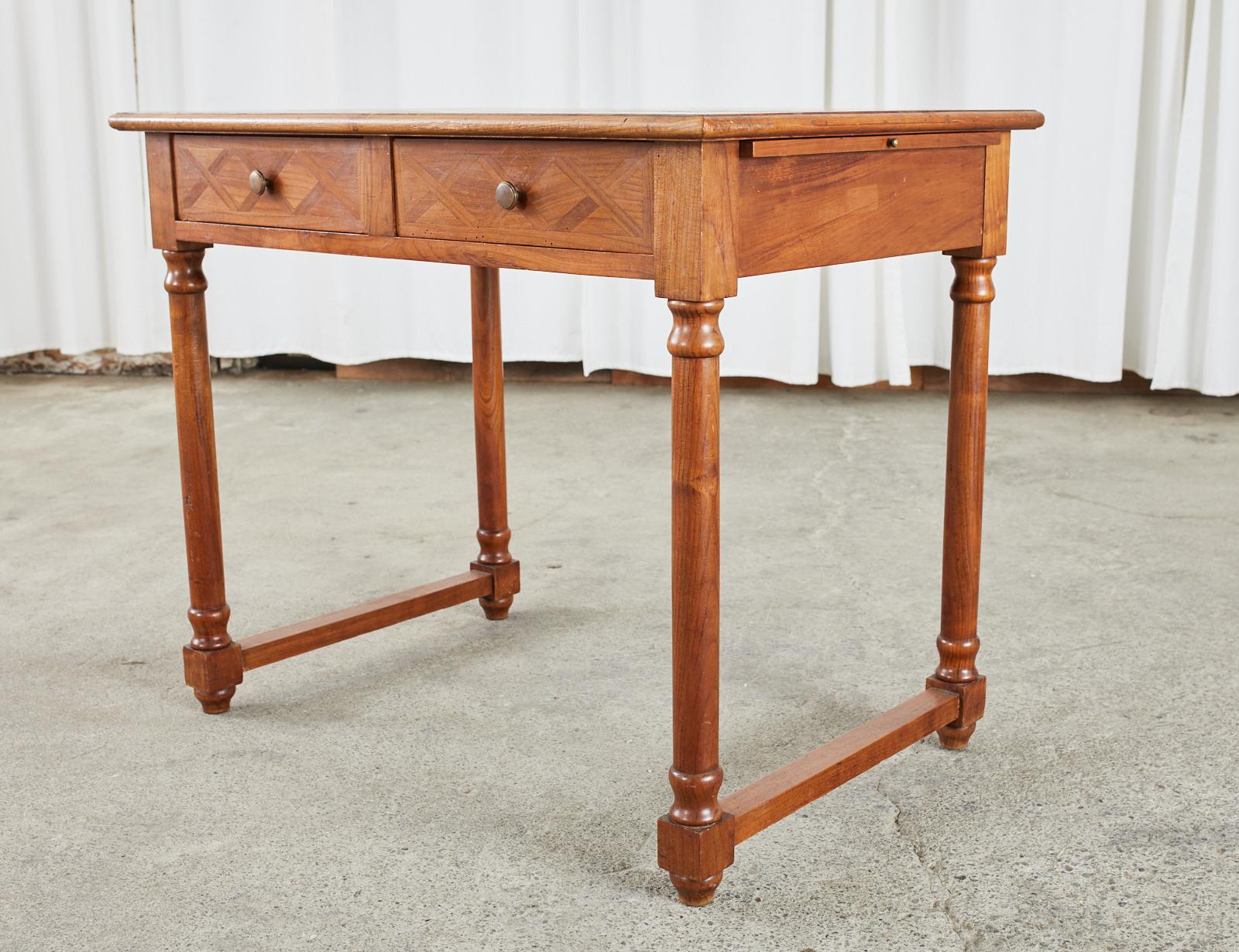 Elegant writing table or desk made on a diminutive scale in the French Louis Philippe taste. The table features an amazing parquetry inlay on the top and drawer fronts having geometric neoclassical style x-form designs. The case is fronted by two