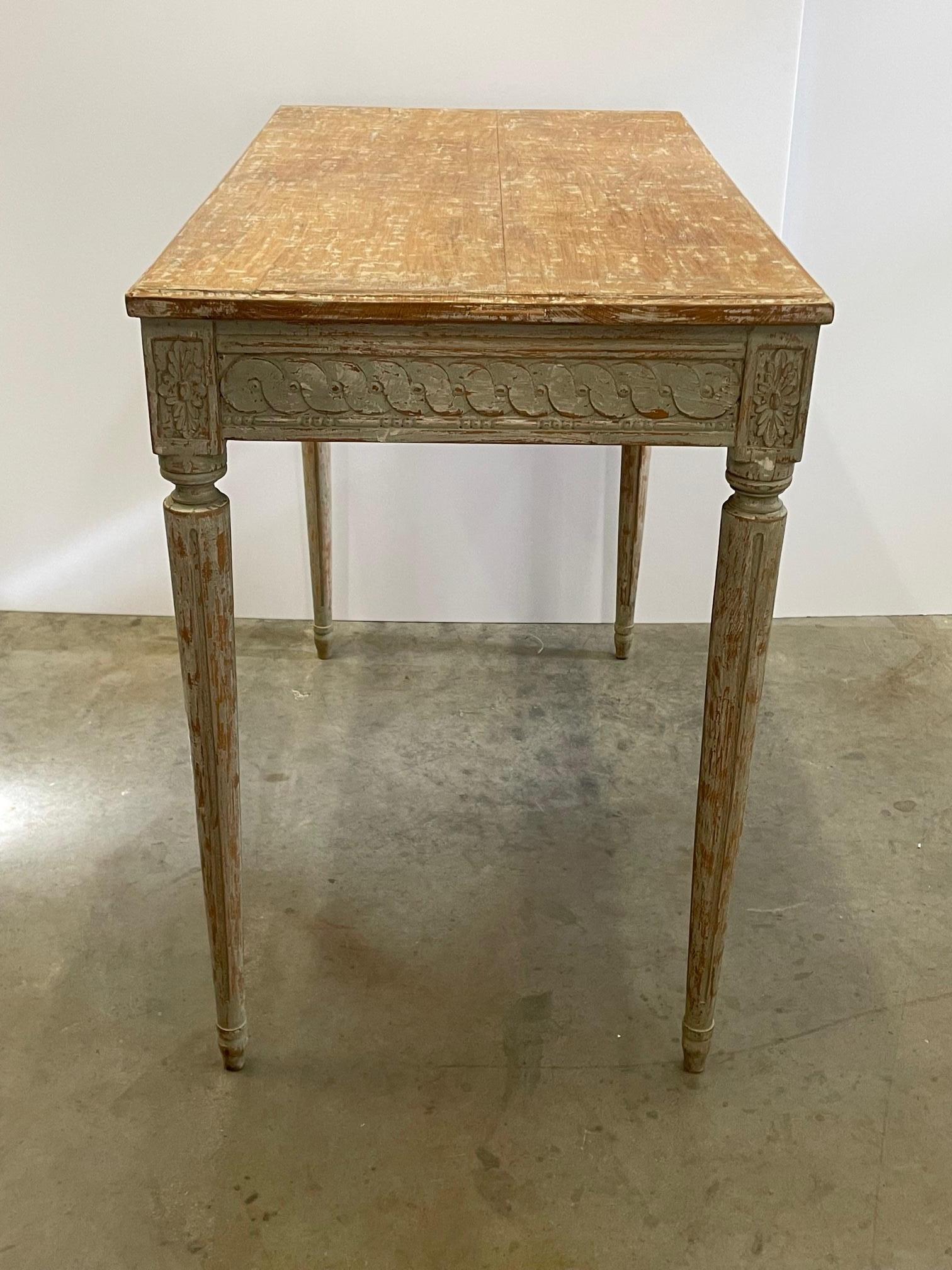 A lovely console table or writing desk of carved wood having a painted light green antique patina with a rubbed finish top, single drawer and tapered reeded legs.
Opening is 25