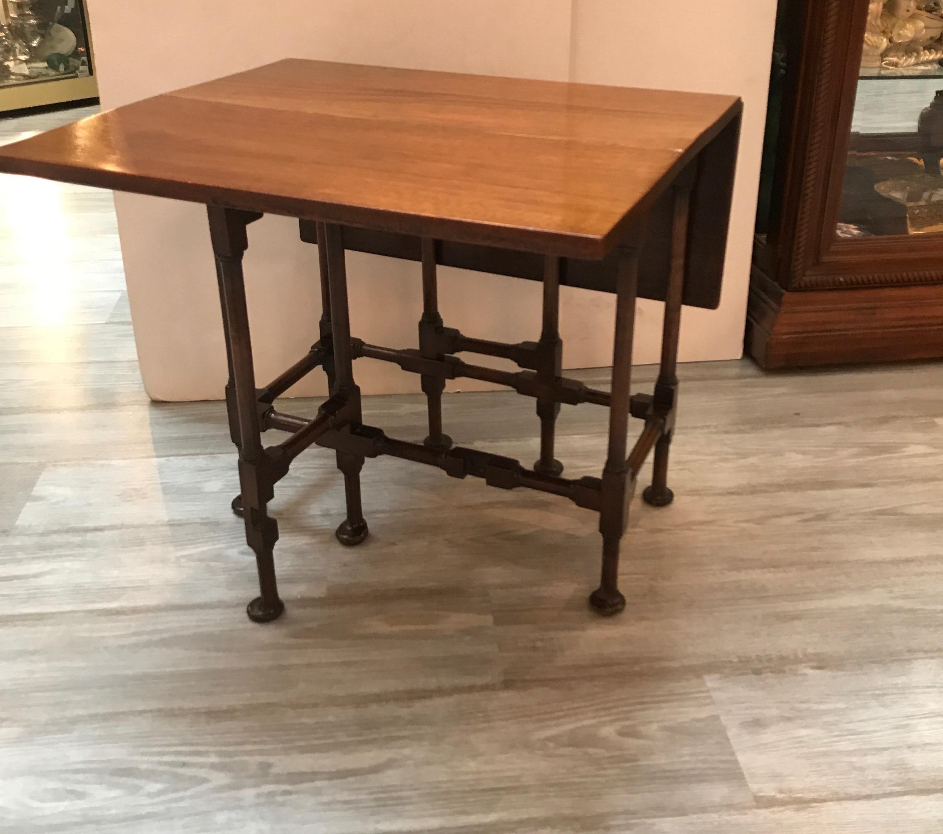 Diminutive mahogany gate leg side table with two drop leaves. The slim table with hand turned legs with spoon feet, each side with a swinging leg the extends to support a leaf/ 10.75 wide,opens to 27 inches. 21.5 inches long, 20 inches high. A great