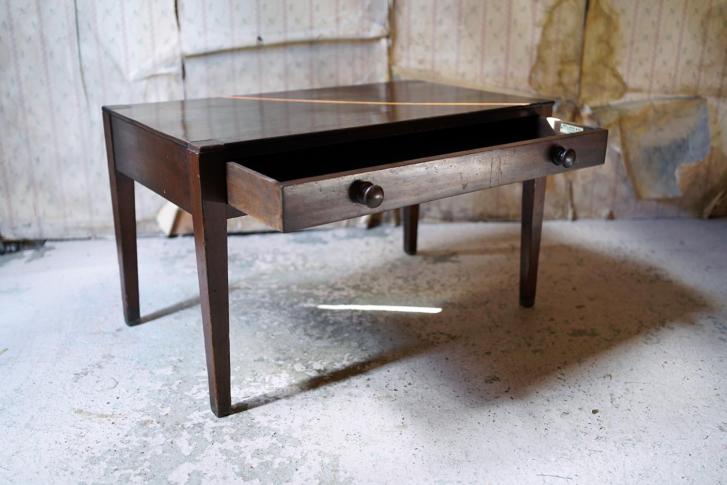 Of unusually small and low proportions the mahogany side table with long frieze drawer and knob handles, bearing ivorine label 'Spillman & Co., St. Martins Lane, London' to the inner drawer, standing on tapering legs and surviving from the first