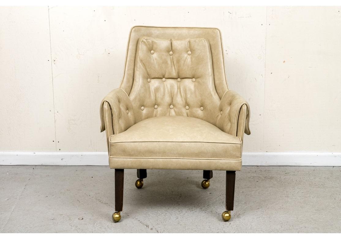 A very well made and  comfortable lounge chair with a fine Mid Century form. The chair with button tufted back and arm pads, tapered and castored wood legs and upholstered in a fine Textured Tan faux leather. 

Dimensions: 28.75” wide by 24” deep by