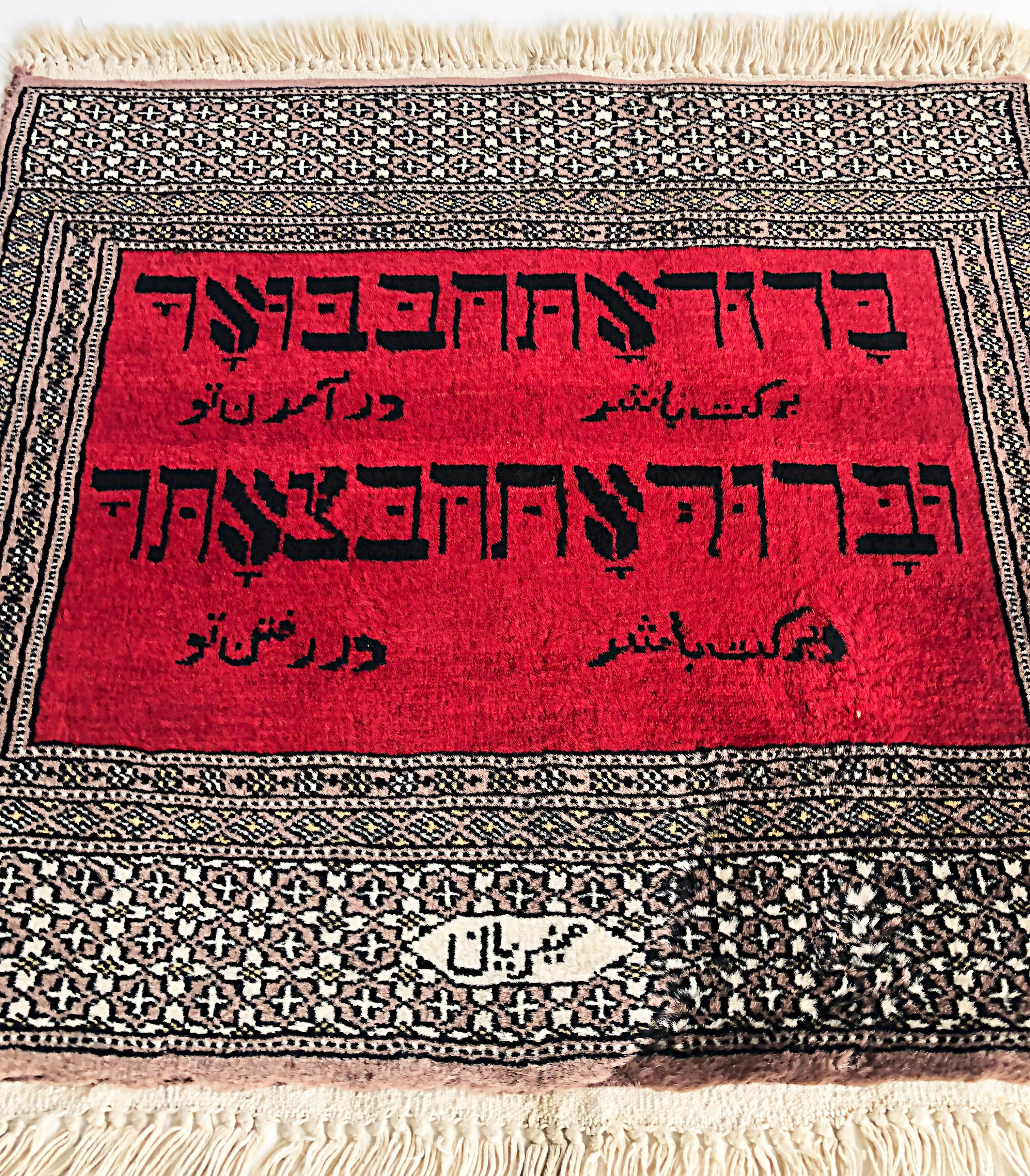 Petit tapis de prière en laine avec texte hébreu, signé.

Nous proposons à la vente un tapis de prière tissé présentant un texte hébreu en deux lignes sur un fond rouge encadré par des bordures florales et géométriques.  Le texte hébreu se traduit