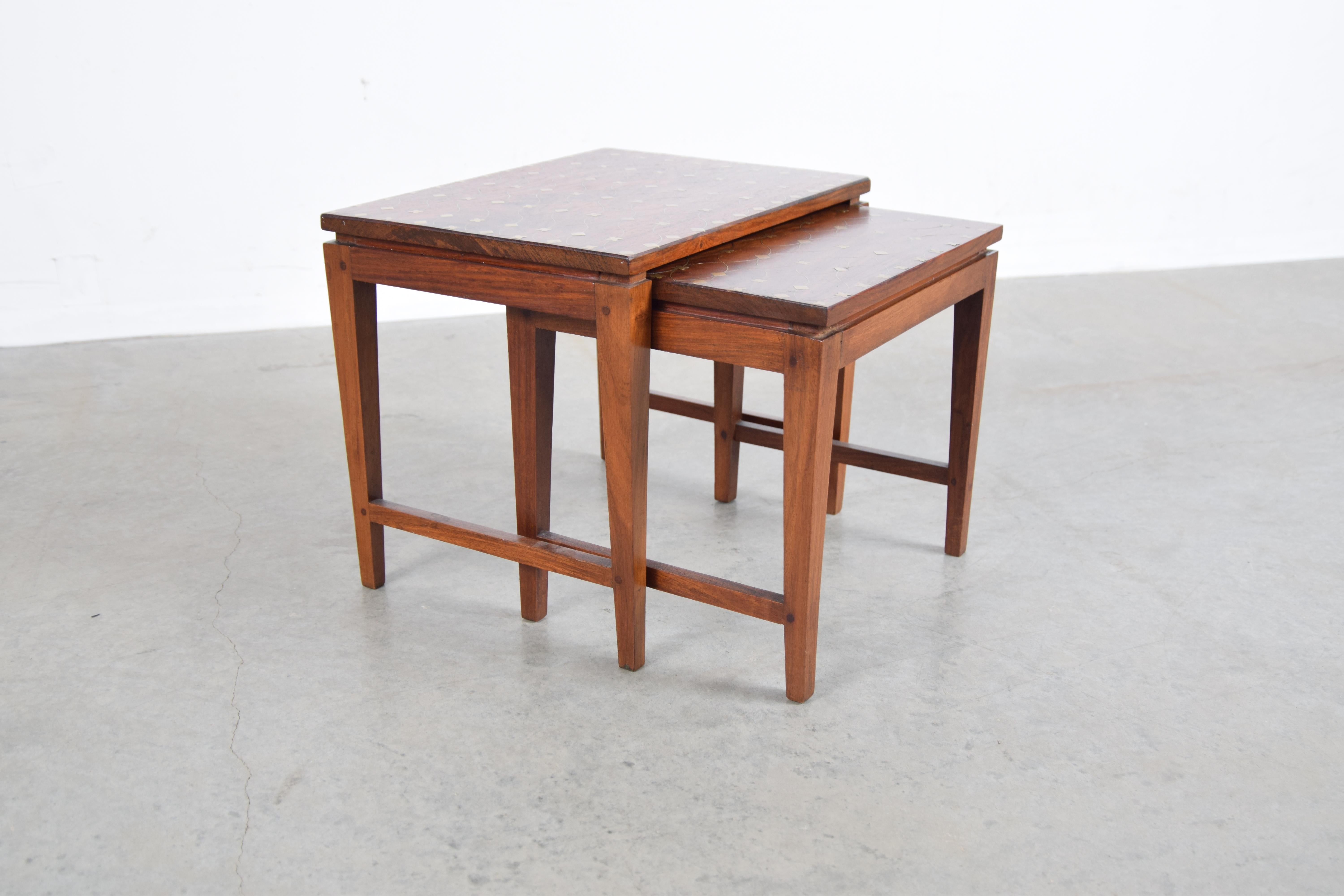 Diminutive set of two solid teak nesting tables with traditional Tarkashi (brass inlay) tops, designed by Indian designer Leela Shiveshwarkar, circa 1960.

Tables measure as follows: Larger table: 14 3/4