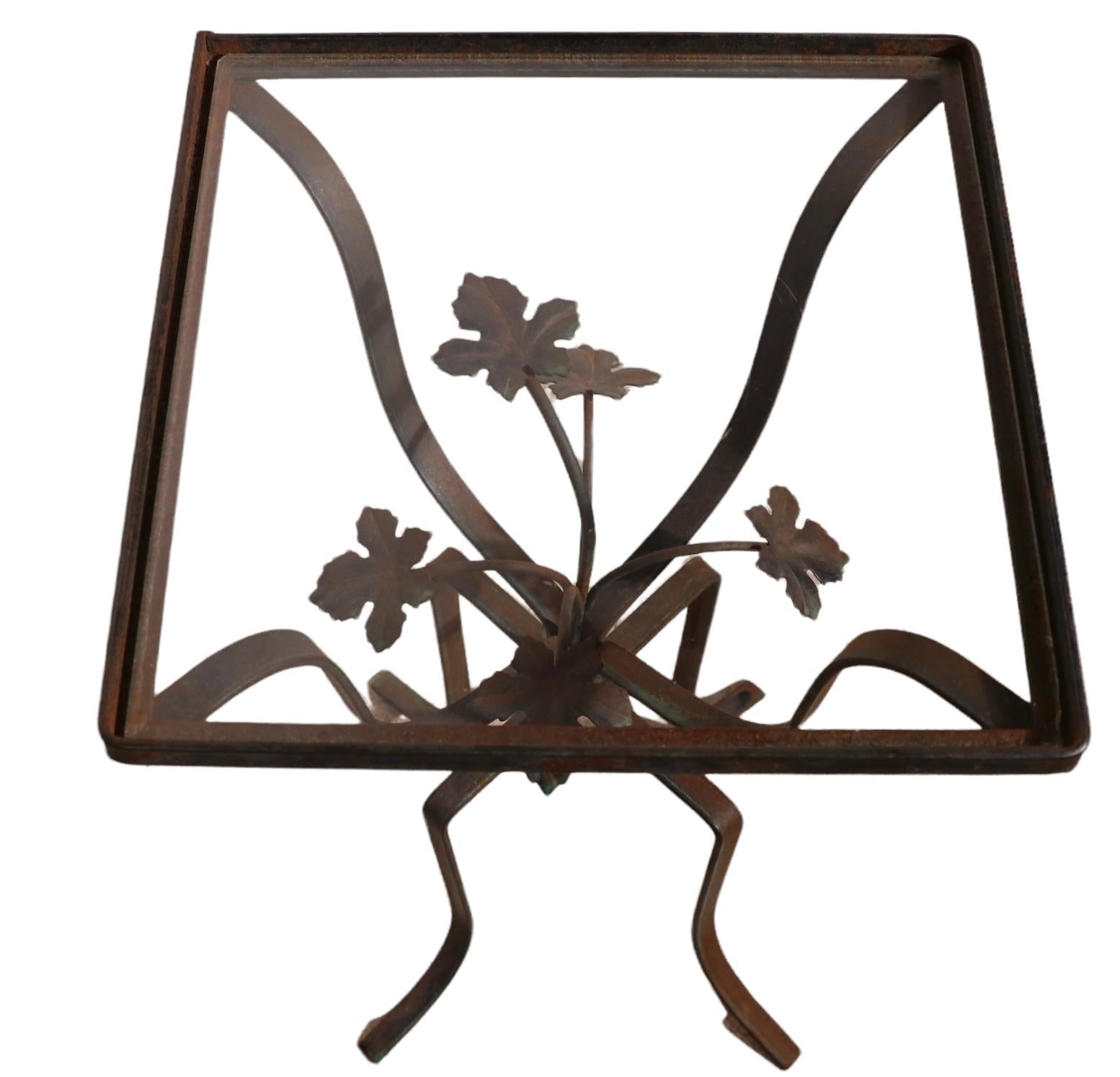 Charming diminutive side, or end table having a wrought iron base with a center floral foliate detail, and a glass insert top. The table is in very good estate condition, the metal finish shows some cosmetic wear, normal and consistent with age,