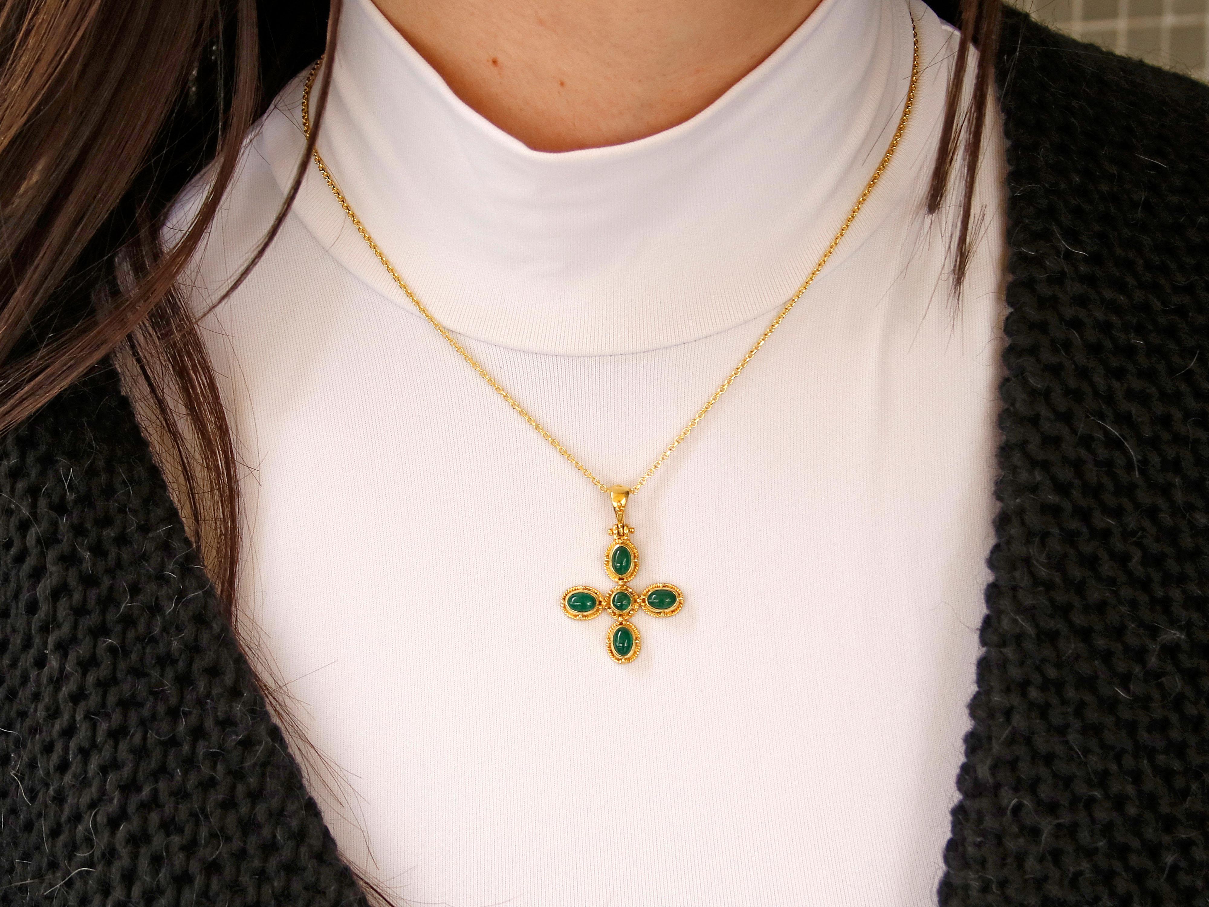 18k gold Byzantine Inspired Cross that showcases intricate design and craftsmanship. This cross features a combination of cabochon emeralds, granulation, and filigree decoration, adding to its luxurious appeal. Emeralds are used as accent stones in
