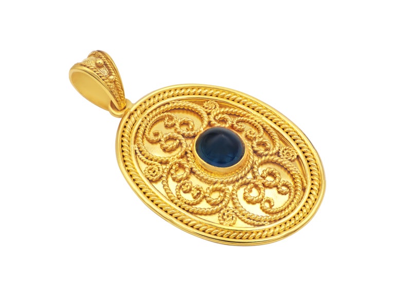 Byzantine inspired pendant in 18k yellow gold with impressive filigrees in many sizes. The center hosts a cabochon Sapphire and the rest we leave it to the light.