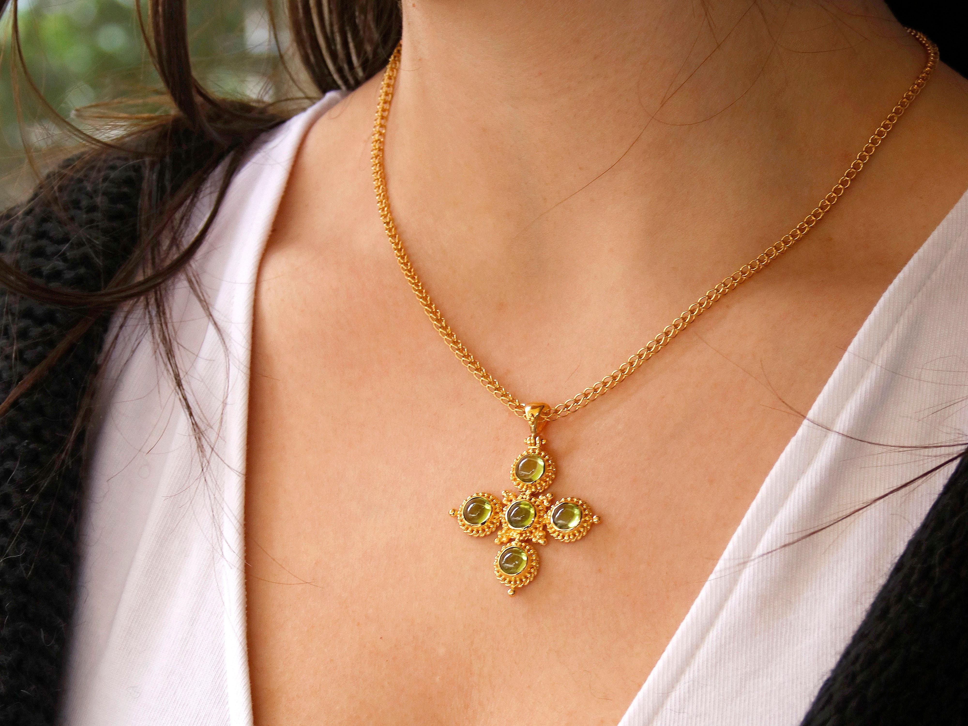 A stunning piece of jewelry, this 18k gold granulated cross features beautiful peridot gemstones and filigree work. The cross pendant is meticulously crafted with granulation technique, which involve placing tiny gold granules onto the surface to