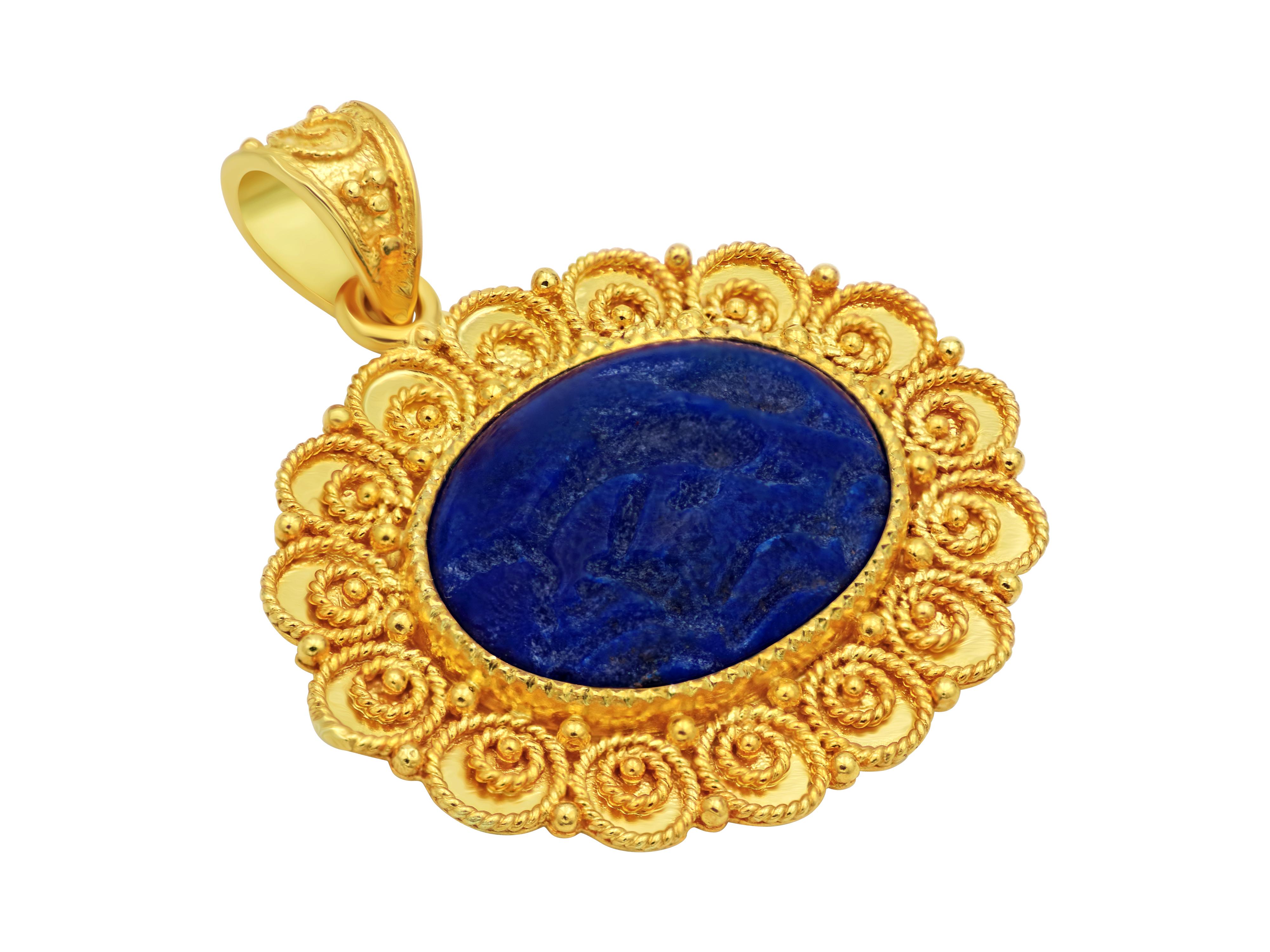 18 karat yellow gold pendant showcasing a solid piece of AAA quality Lapis Lazuli in a deep blue color with carved dolphins the symbol of love.  The setting is formed by filigrees graduation geometrically placed all around the oval. 
Simple gorgeous