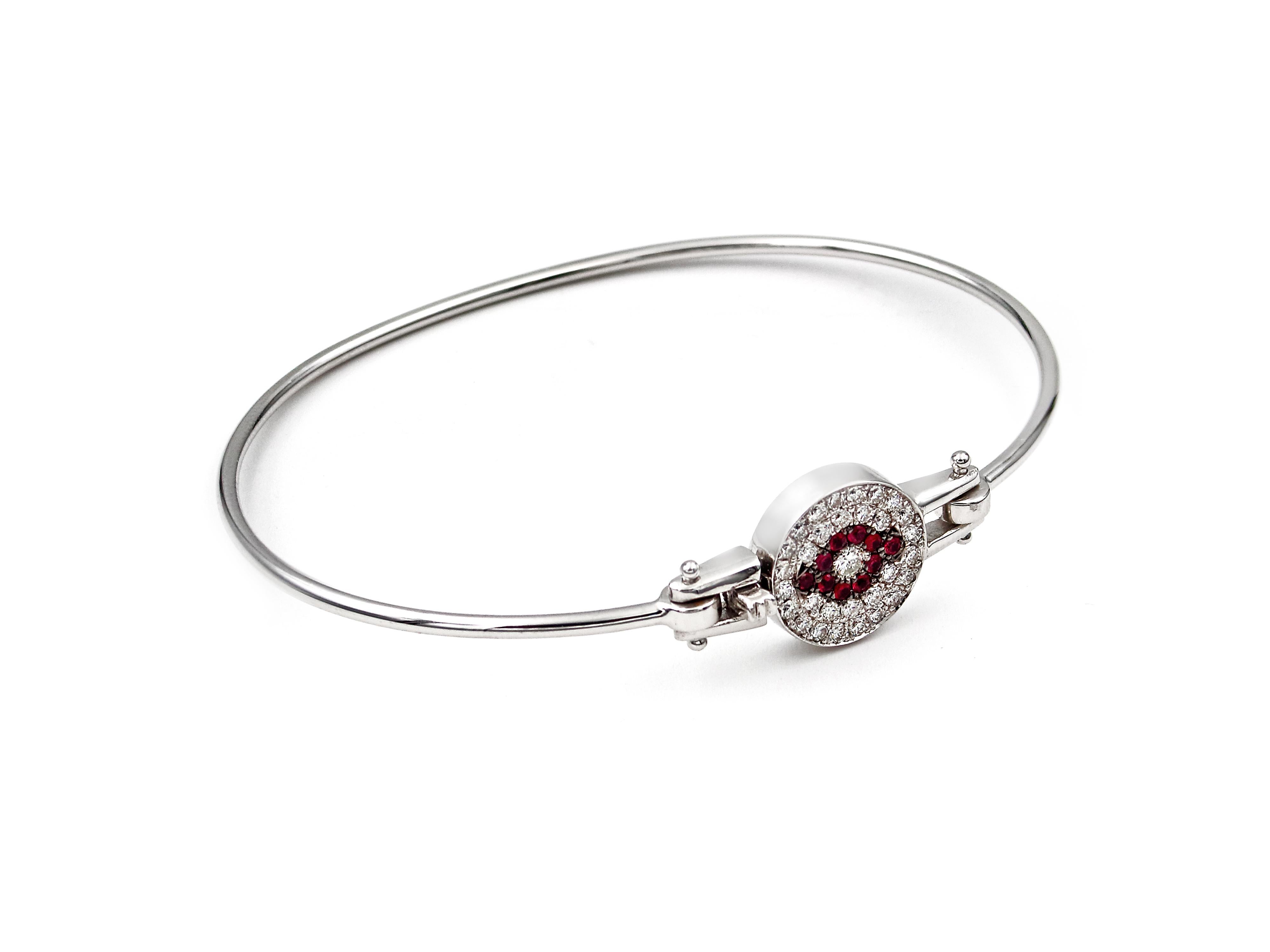 The first evil eye on a bangle bracelet. A solid 18k white gold bangle wire that hosts 0.43 karats brilliant cut diamond circle with 0.13 karats rubies forming the famous evil eye that is there to wear  off the negative energy and protect you from