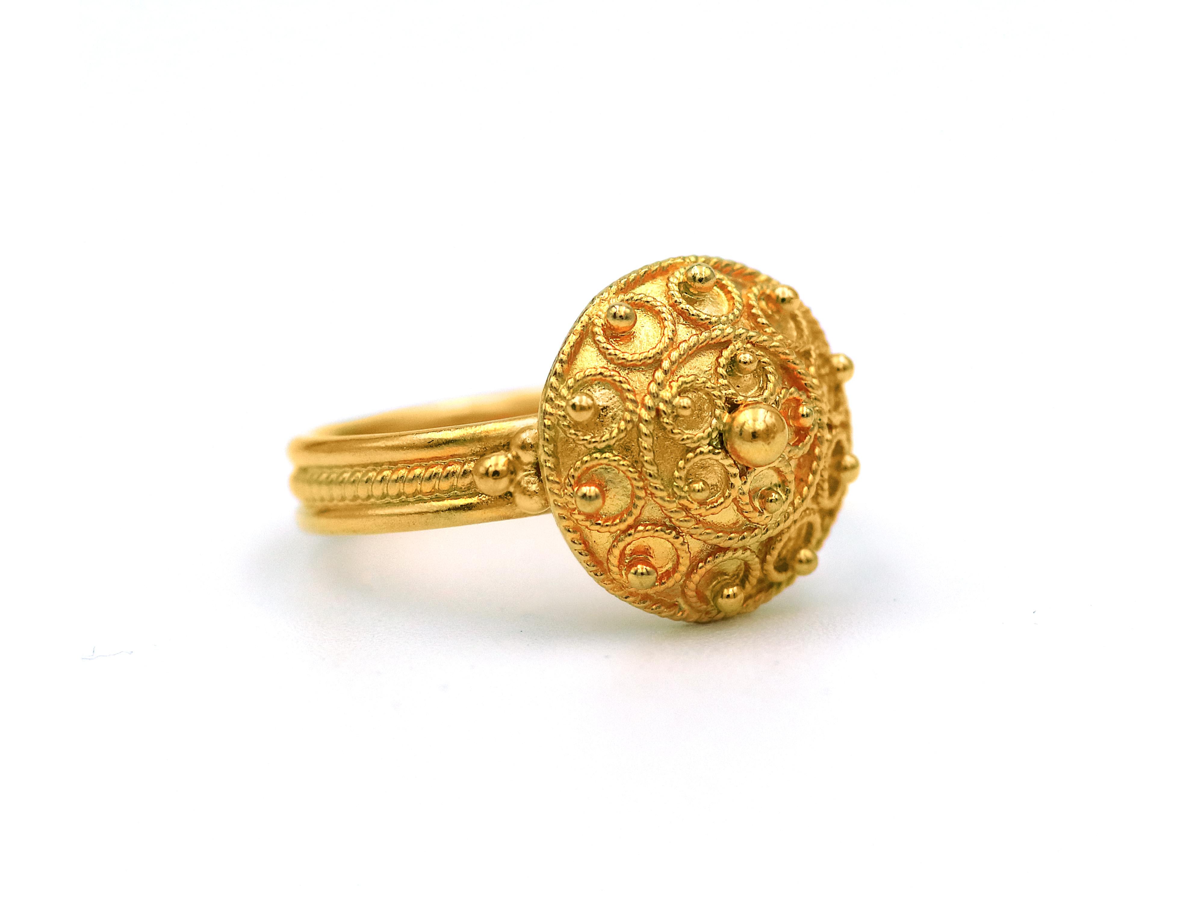 Bocola design ring set in 22k yellow gold with circles of filigree and granulations of different size all around that half round ring. Each side ties the upper and bottom part with three granulations creating a pyramid and the band also with