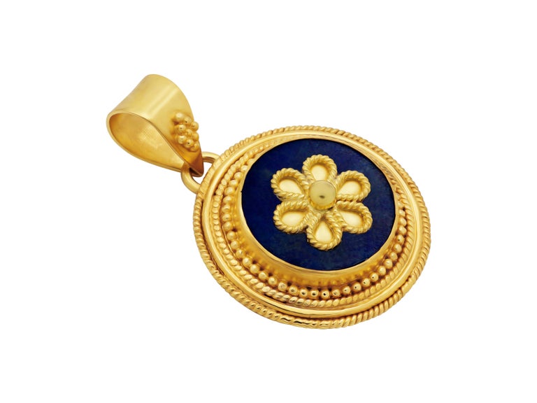  A neoclassical era pendant in 22k yellow gold with several circles of filigree wires, granulation and a round Lapis lazuli with a daisy in center catching every eye. 
