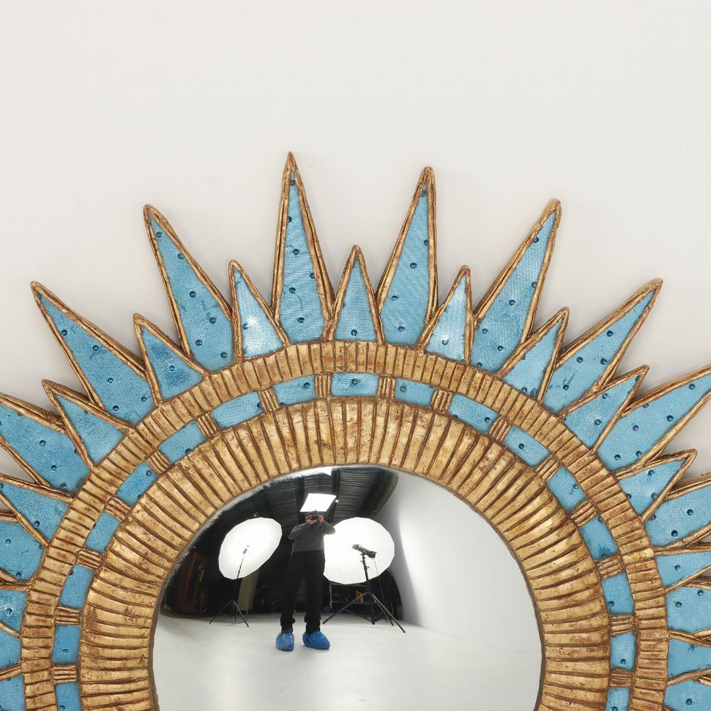 A fine blue dimpled and textured glass and resin convex mirror within sunburst frame in the style of the famous 