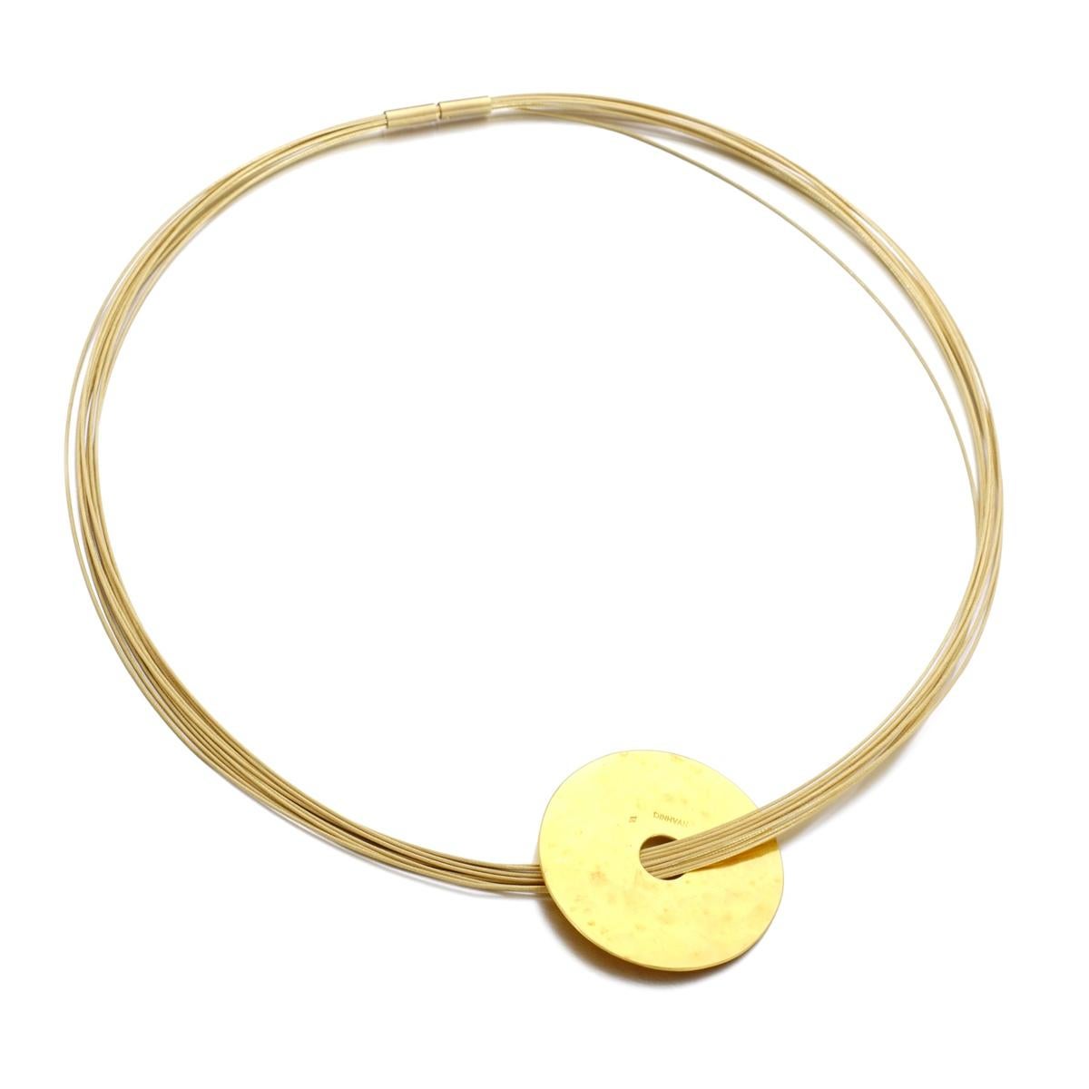 An incredible Dinh Van pendant necklace showcasing a hammered disc suspended by a multistranded braided cable necklace in 18k yellow gold. The necklace measures 16.5