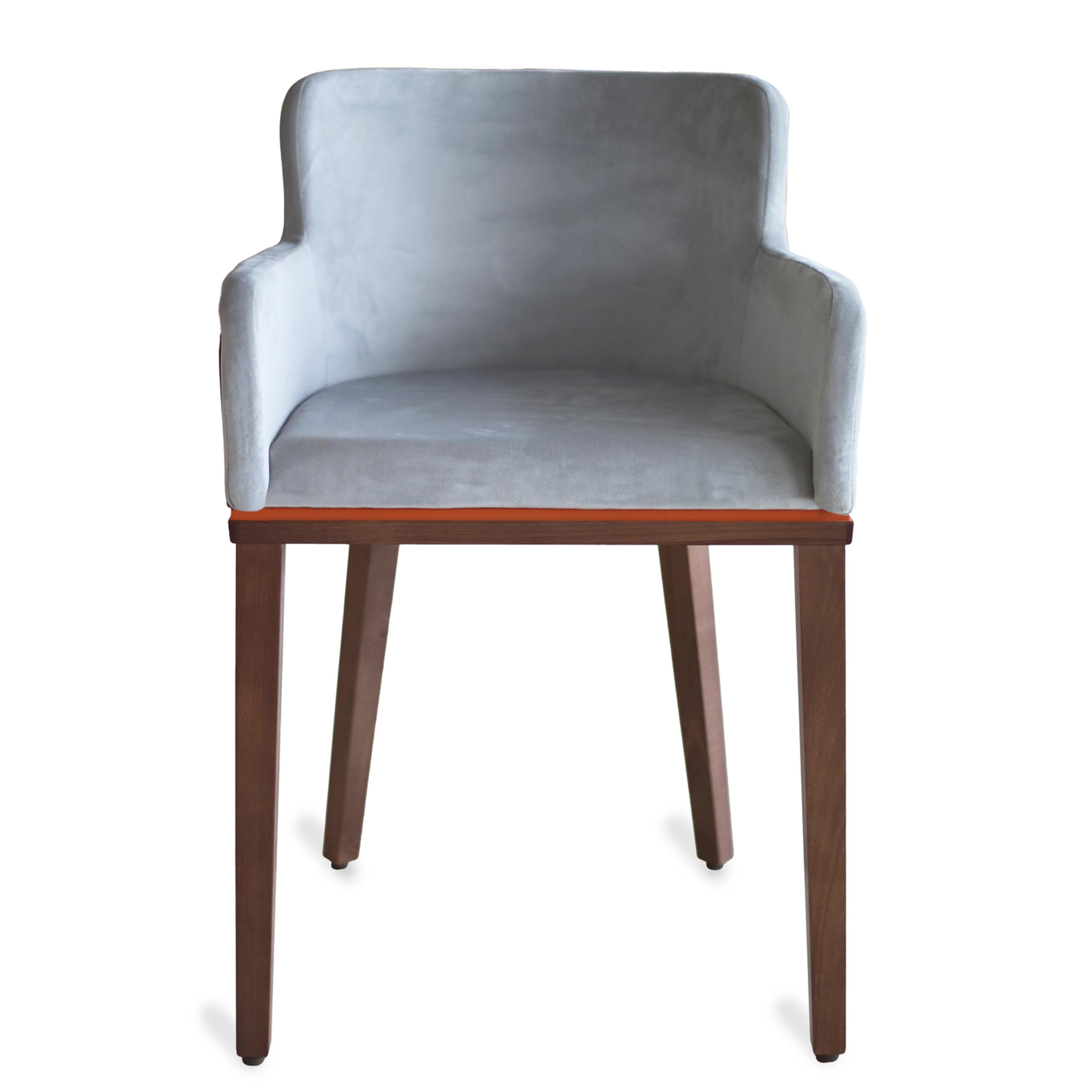 This dining chair's unique feature lies in the upholstery design which flows beyond the seat of the dining chair. The chair's structure is made using walnut with orange detailing just below the seat. The seat and back are upholstered in soft velvet