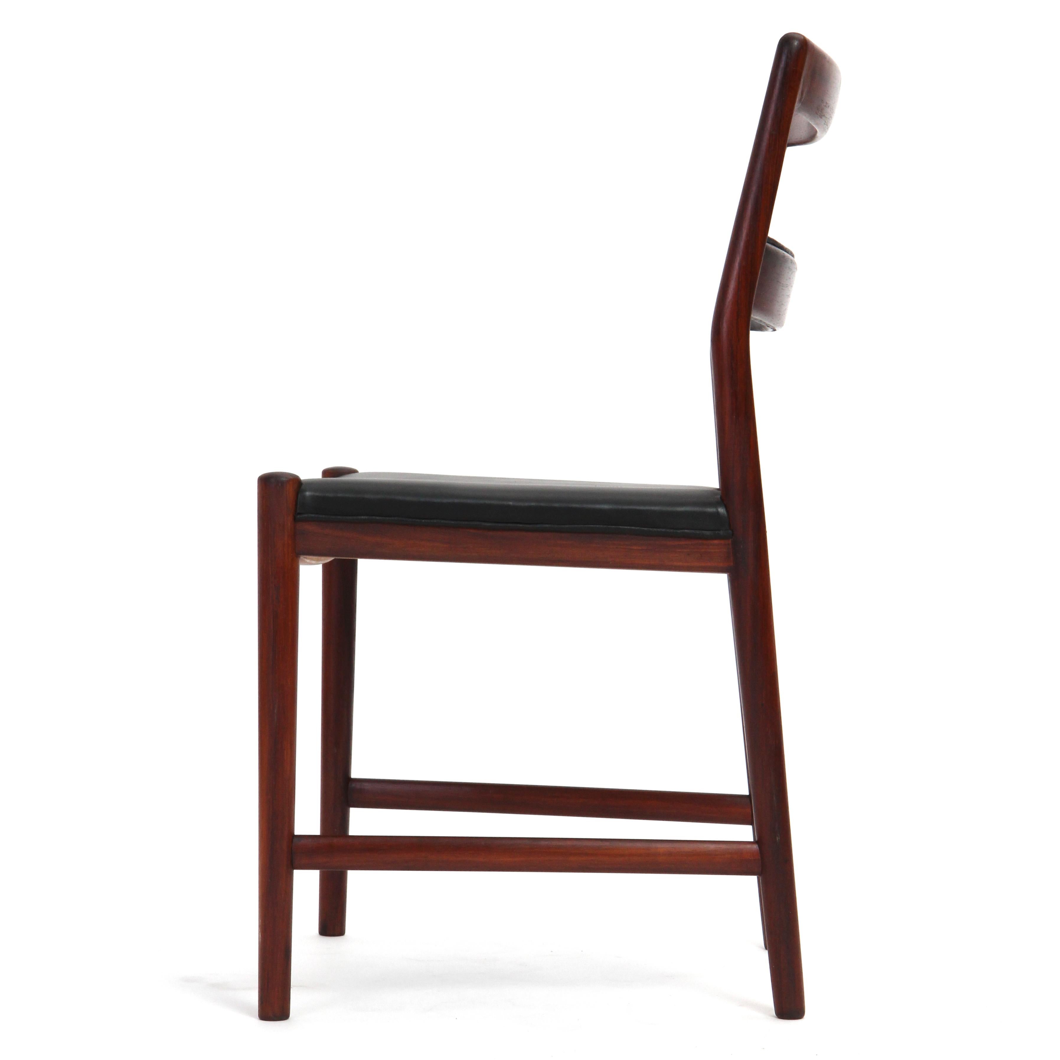 A Scandinavian Modern ladder back dining chair by renowned Danish designer Helge Vestergaard-Jensen. This sculptural chair features a luminous Brazilian rosewood frame with black leather seat and leather-wrapped center slats. Crafted in Denmark by