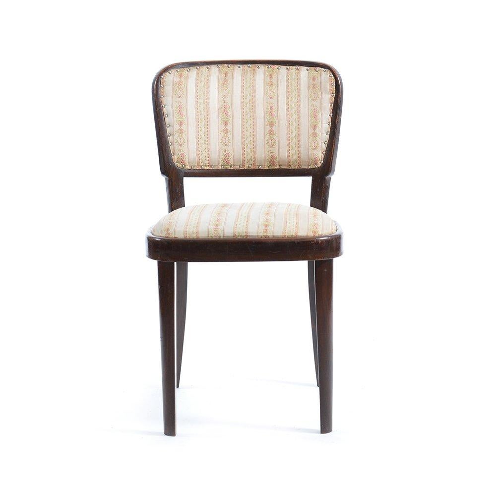 Élégante chaise de salle à manger produite par la société Thonet dans un état original. La chaise est fabriquée en bois de chêne robuste avec une assise et un dossier rembourrés. Le tissu est de la soie vintage. Une certaine patine est visible sur