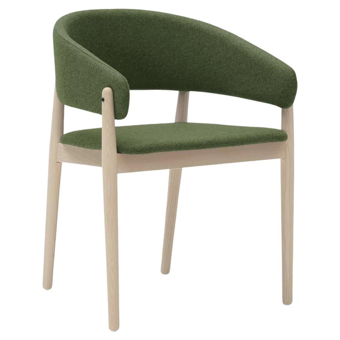 A large arched wrap-around backrest is the element from which this design is visually articulated. This is supported at four points, by blunt wooden bars that are lowered to the floor turning into legs.
A warm contrast is established between the