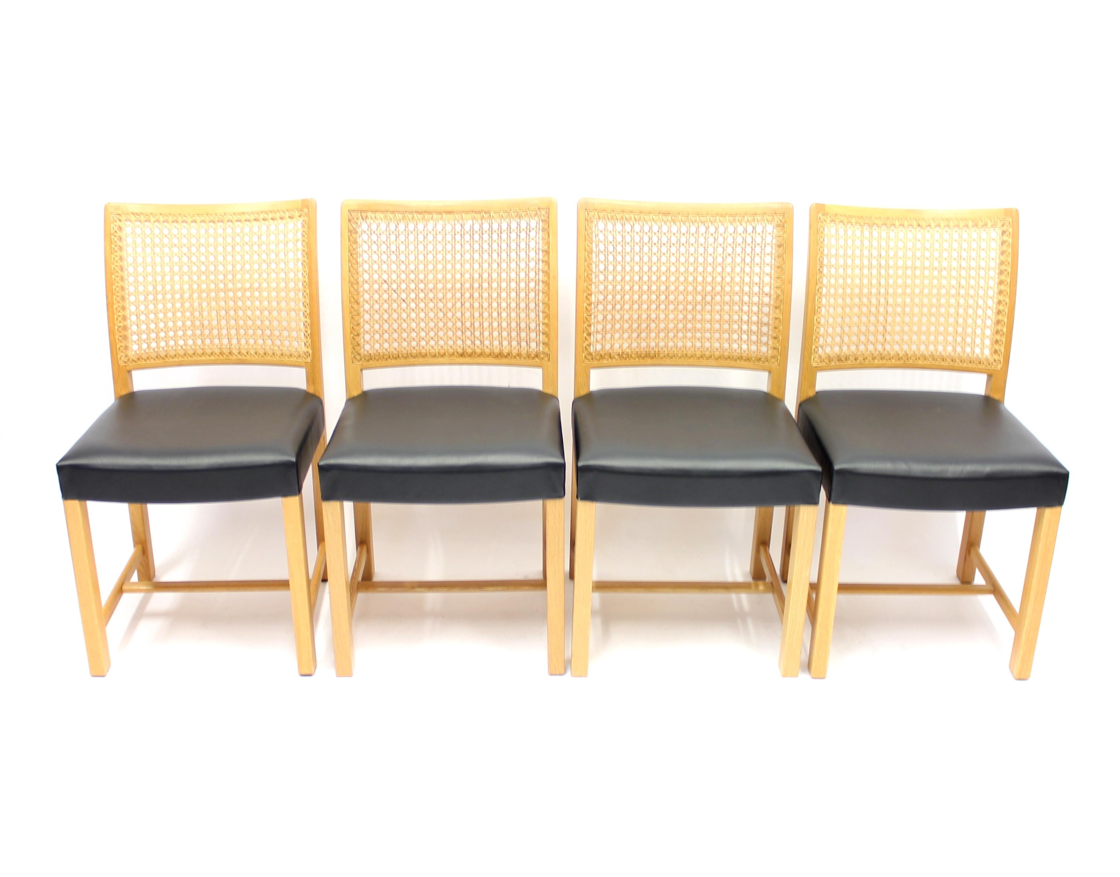 Set of 4 dining chairs designed by Carl Gustaf Hjort af Ornäs for Mikko Nupponen in the 1950s. Frame and legs of solid oak, cane back and new black leather upholstery on the seats.
