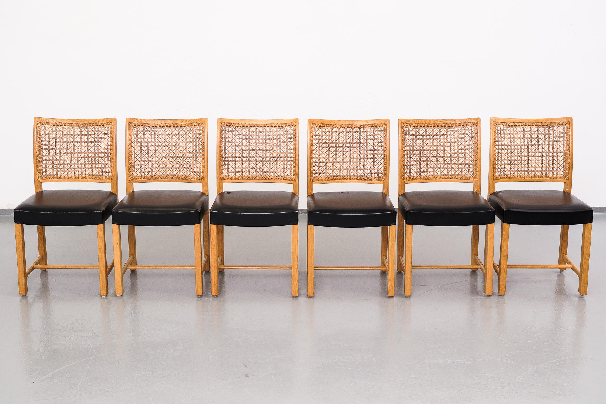 Set of six dining chairs designed by Carl Gustaf Hiort af Ornäs for Mikko Nupponen in the 1950s. Frame and legs of solid oak, original rattan back and black leather upholstery on the seats.