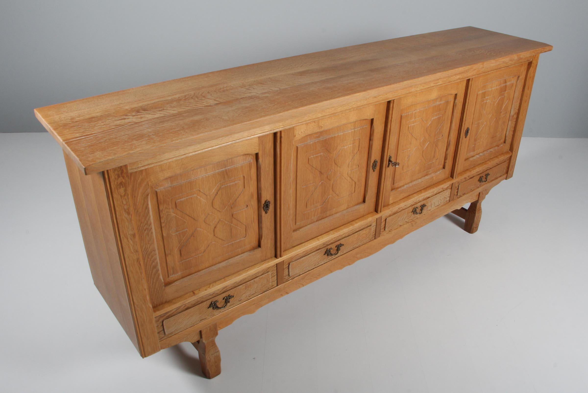 Striking highboard in oak with rich carved details. Attributed to Henry Kjærnulf. 

Refreshing design with bold Baroque coming together nicely with Mid-Century Modernism.

Probably made by EG møbler in the 1970s.
 