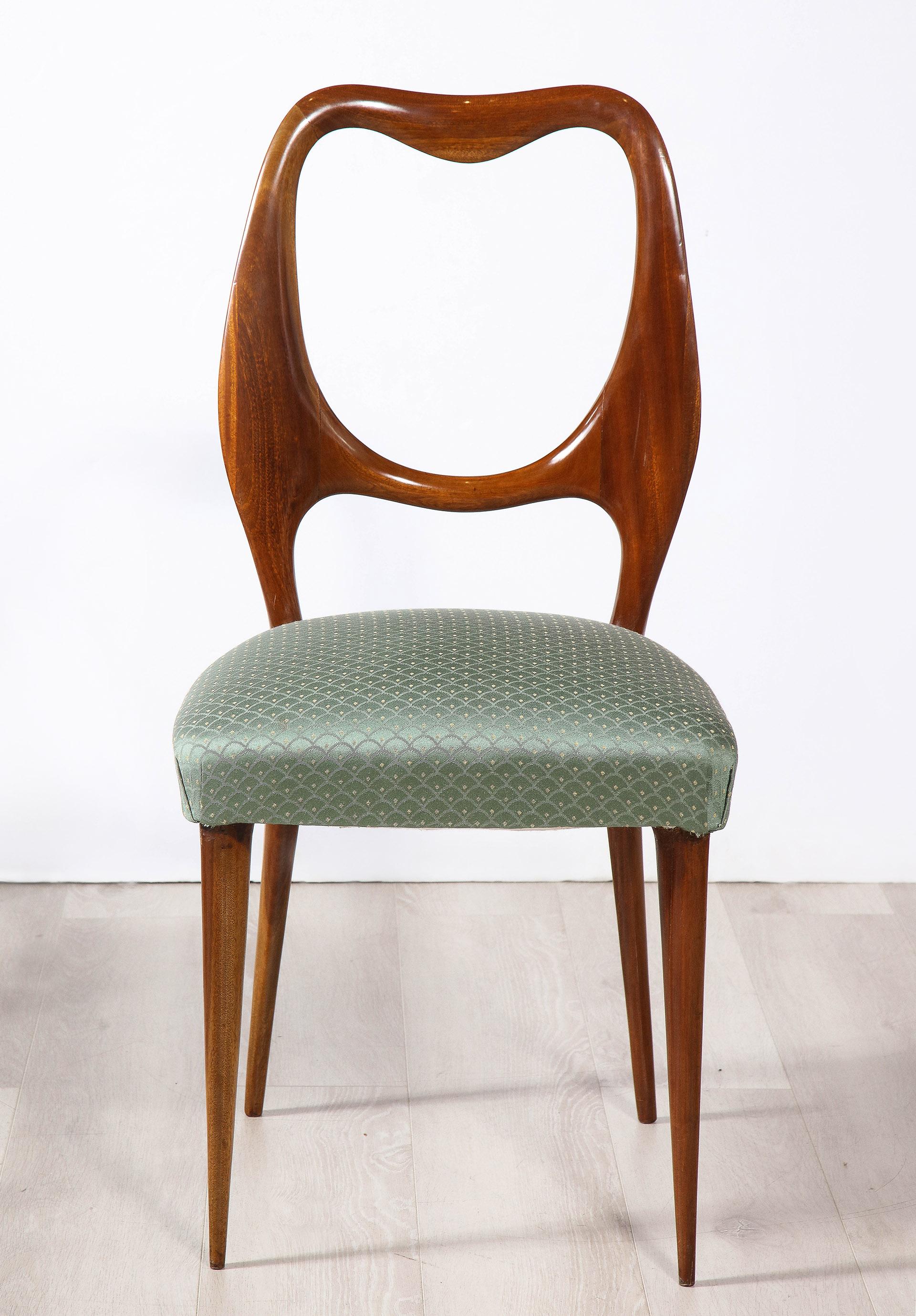 The set of 4 mahogany dining side chairs each with a unique open back and upholstered seats, raised on tapering legs. 